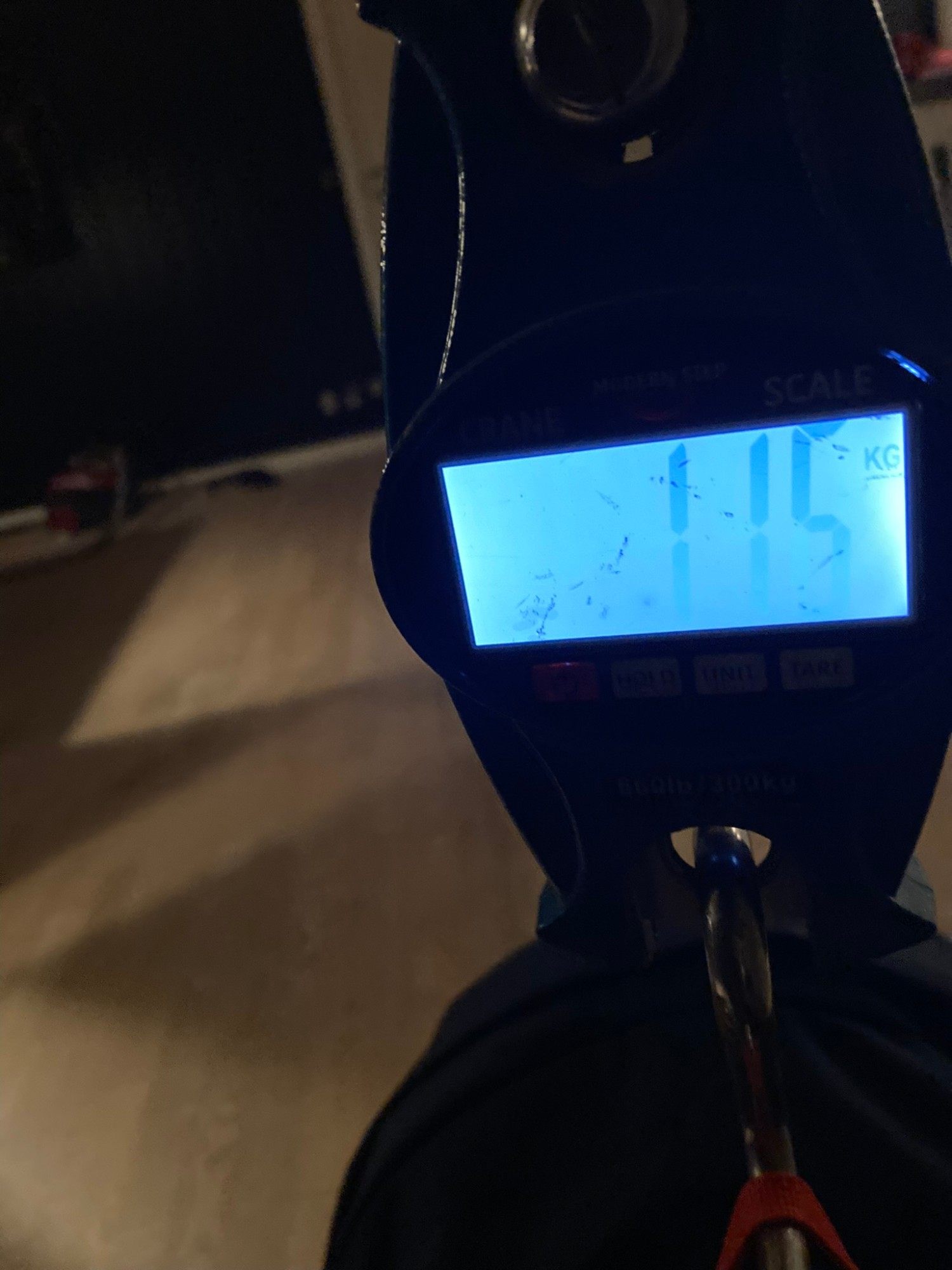 A hanging luggage scale showing 11.5 kg