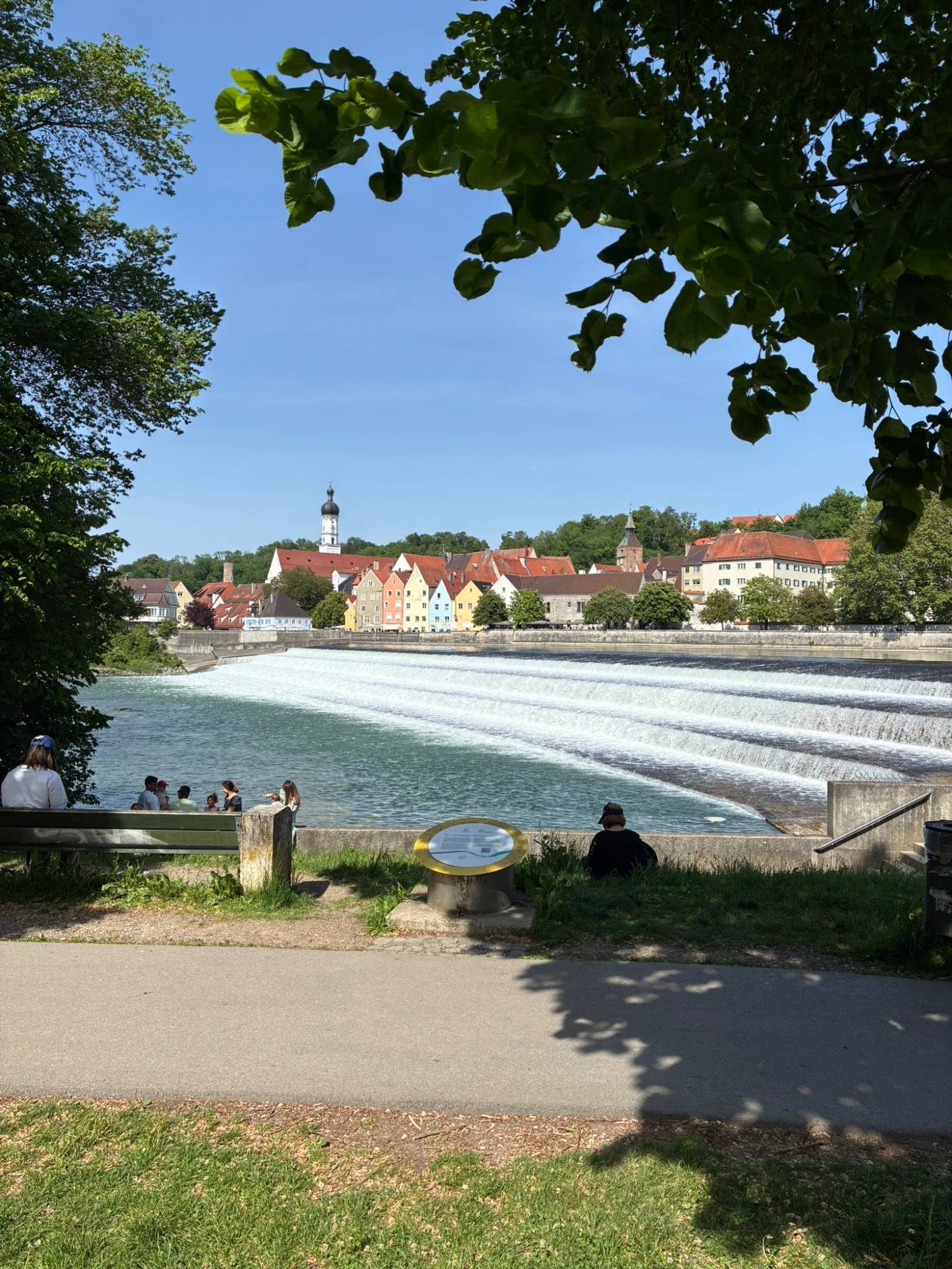 The Lechwehr weir in Landsberg am Lech with colourful old houses and a church tower behind