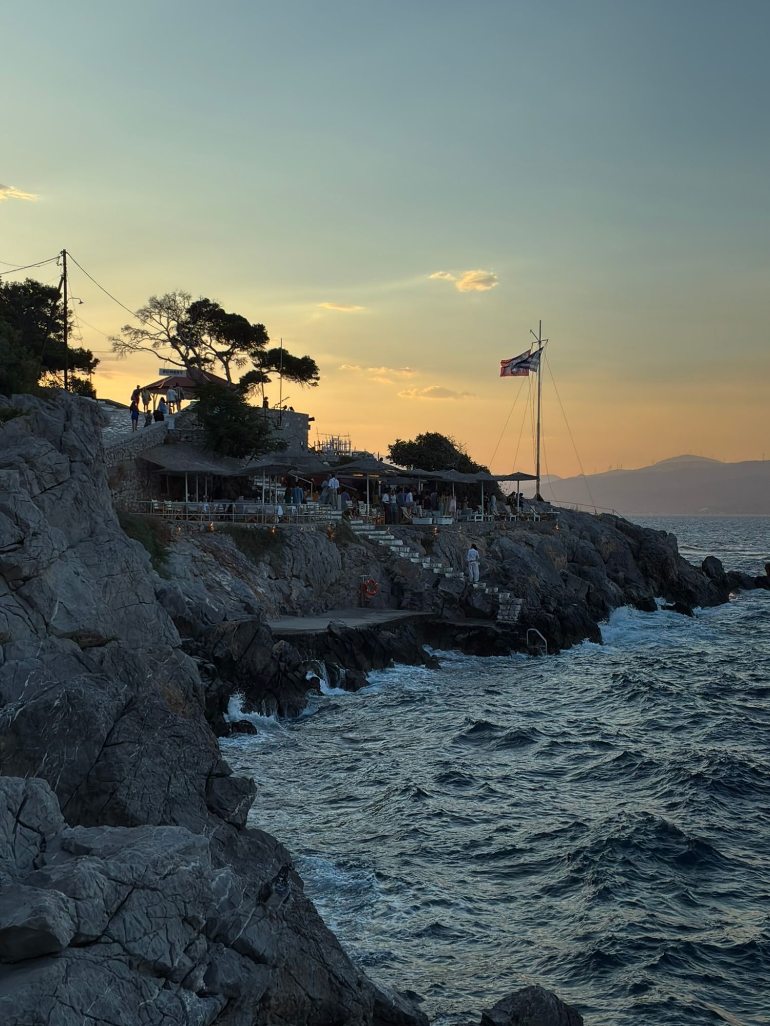 People gathering on the rocky coast just west of Hydra Town as the sun goes down