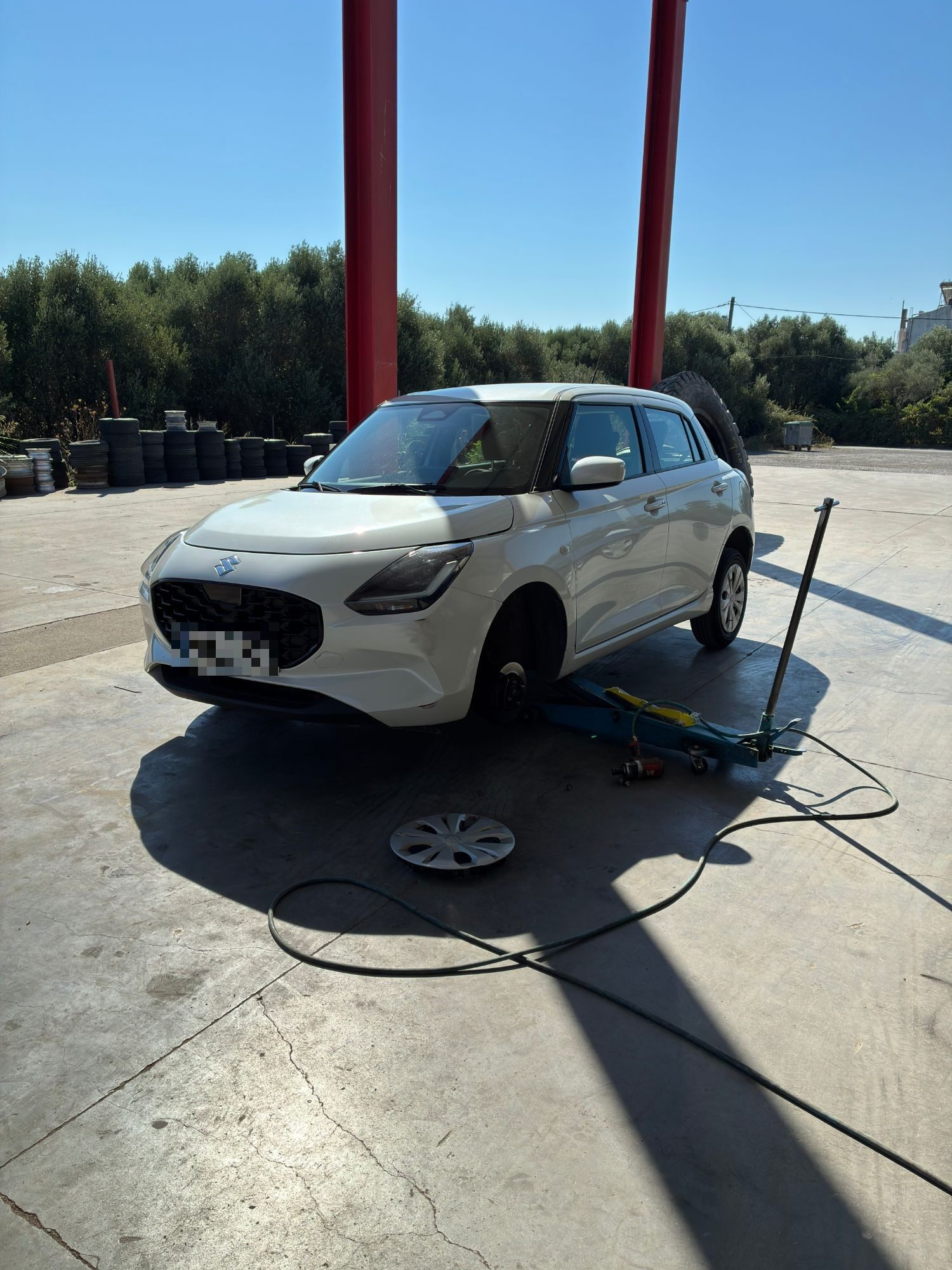 Our white rental car jacked up without its front wheel at a tyre workshop near Sparta