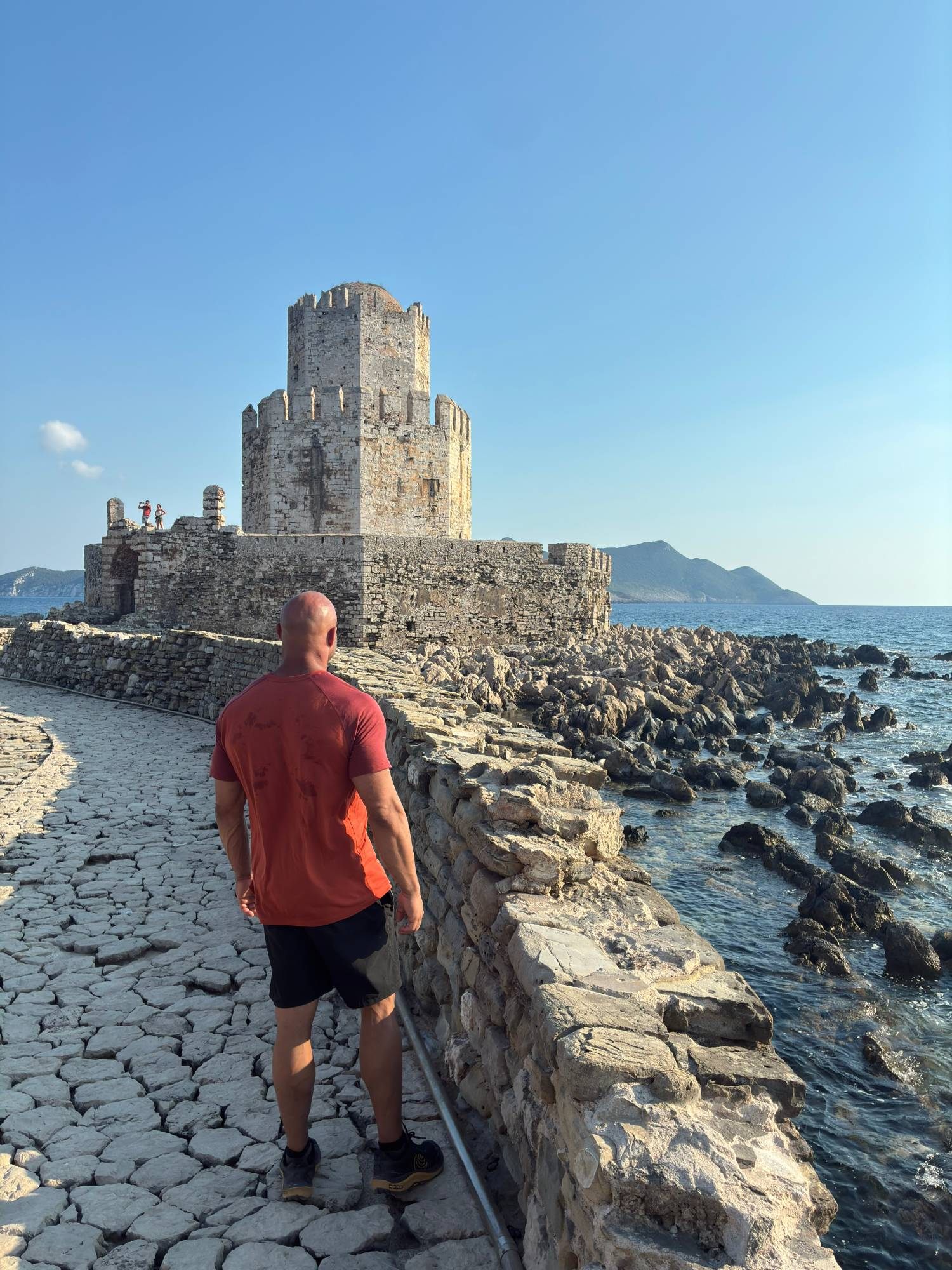 Walking along the stone causeway towards the Bourtzi tower at Methoni