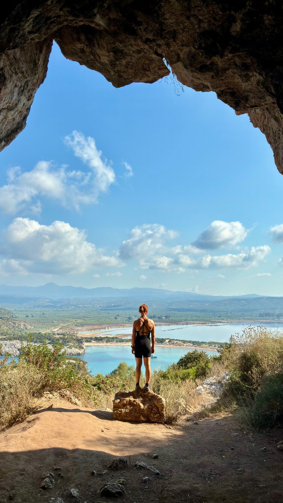 Kristine standing at the mouth of Nestor's Cave looking out over Voidokilia Beach and Gialova Lagoon