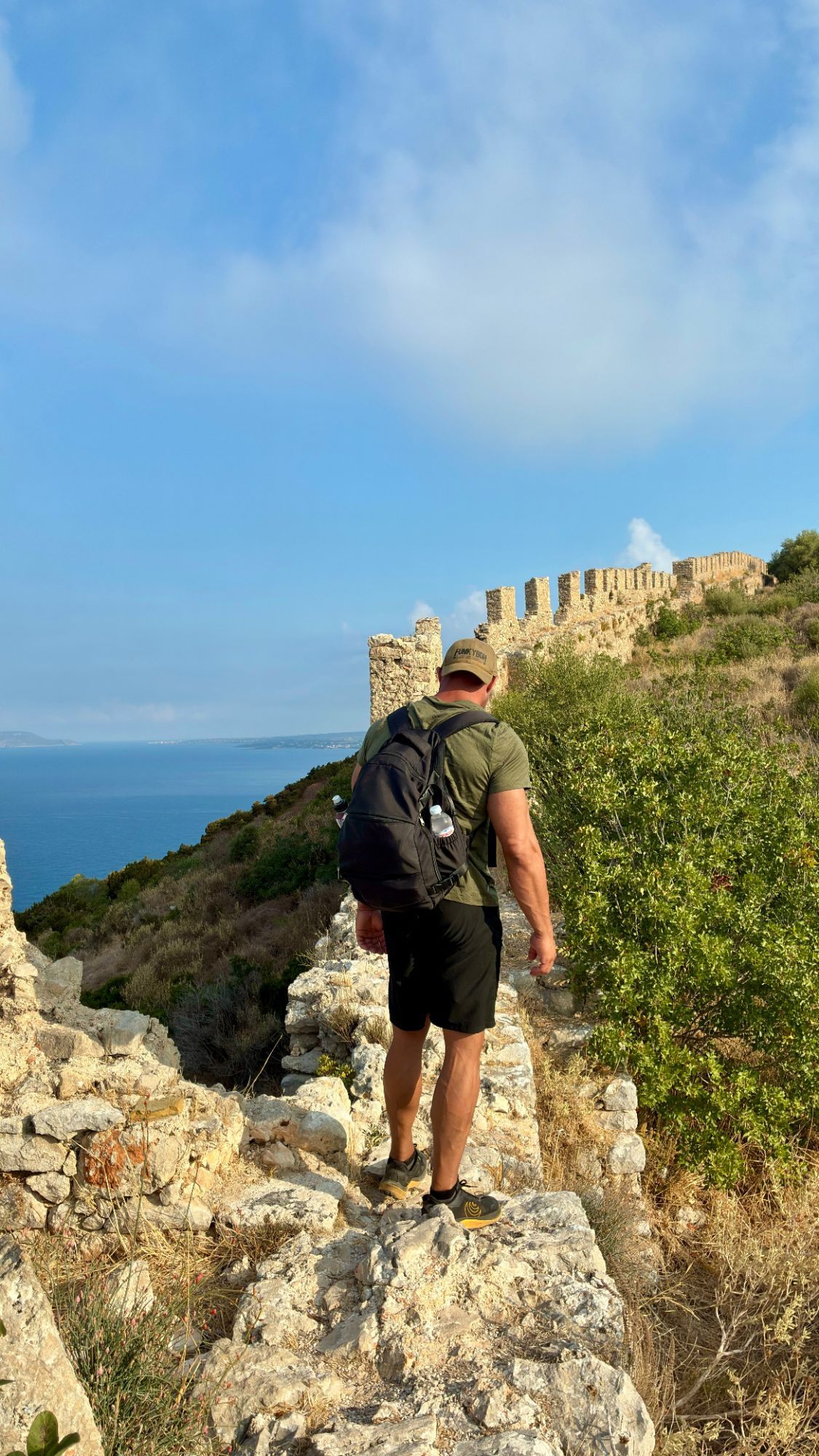 Walking along the crumbling walls of Old Navarino Castle, with battlements ahead and the sea below