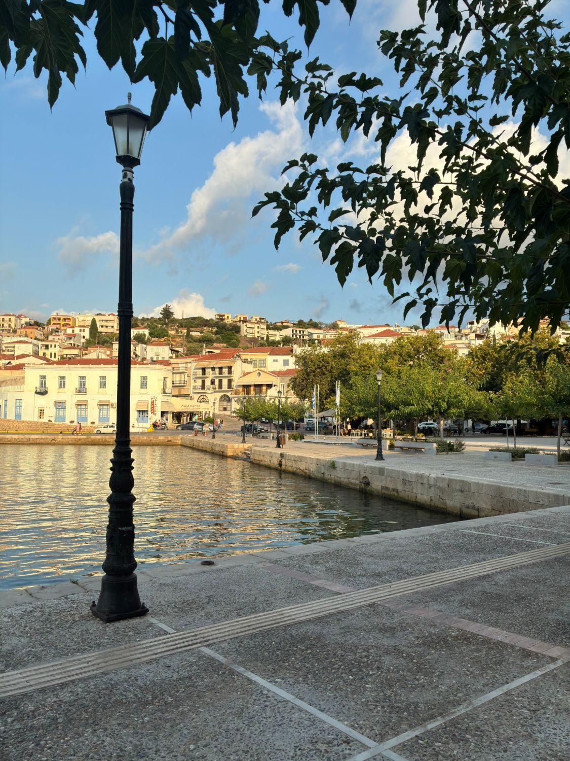 The harbour front of Pylos with an old street lamp and houses climbing the hill