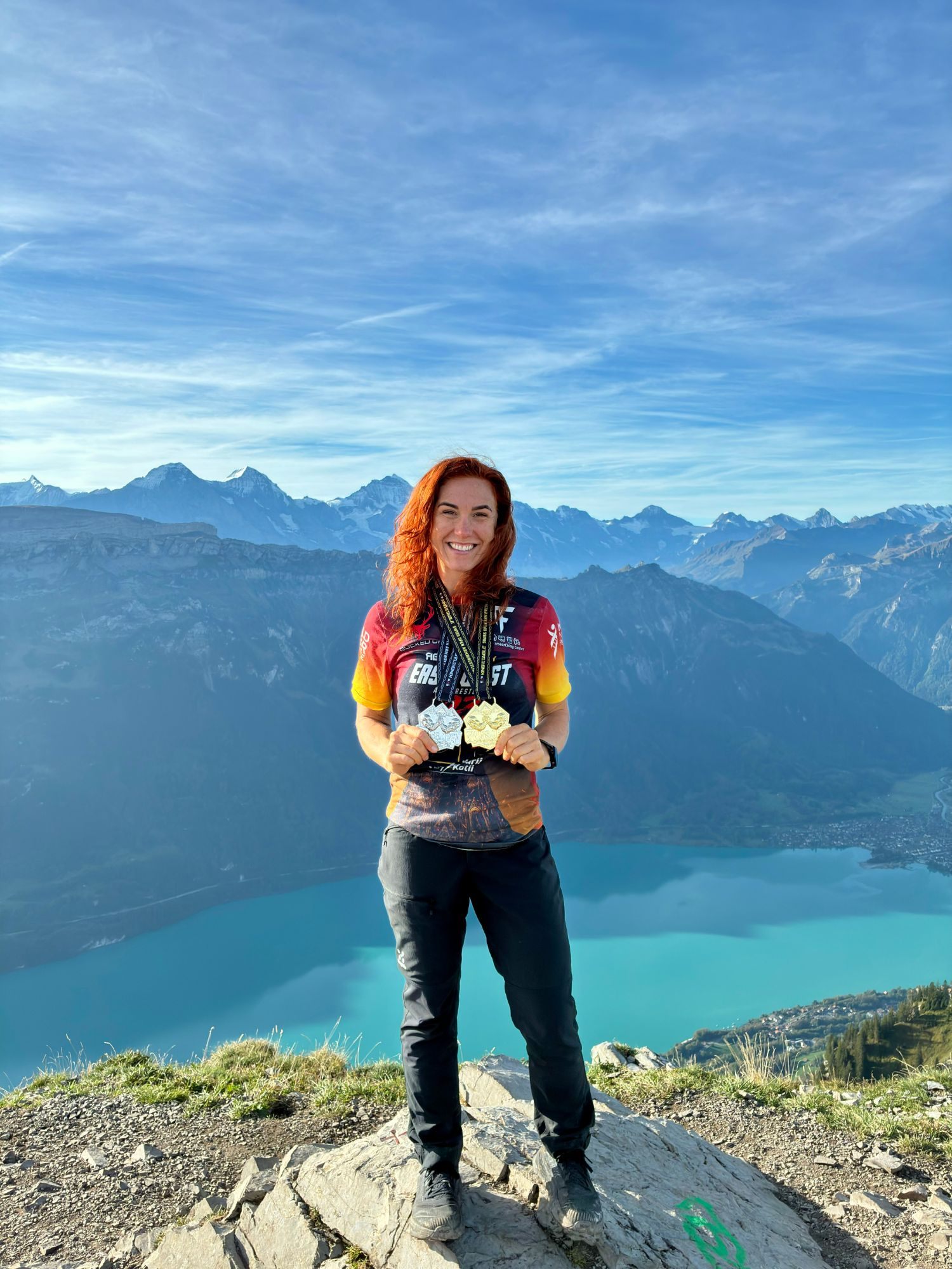 Kristine smiling on the summit of the Augstmatthorn with Lake Brienz and the Alps behind