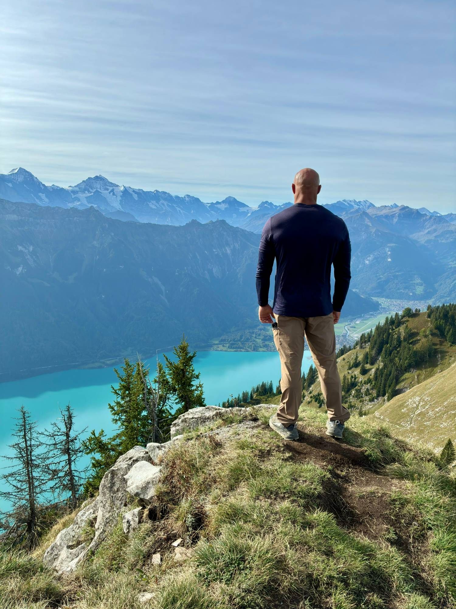 Standing on a grassy outcrop above the turquoise Lake Brienz with snow-capped Alps in the distance