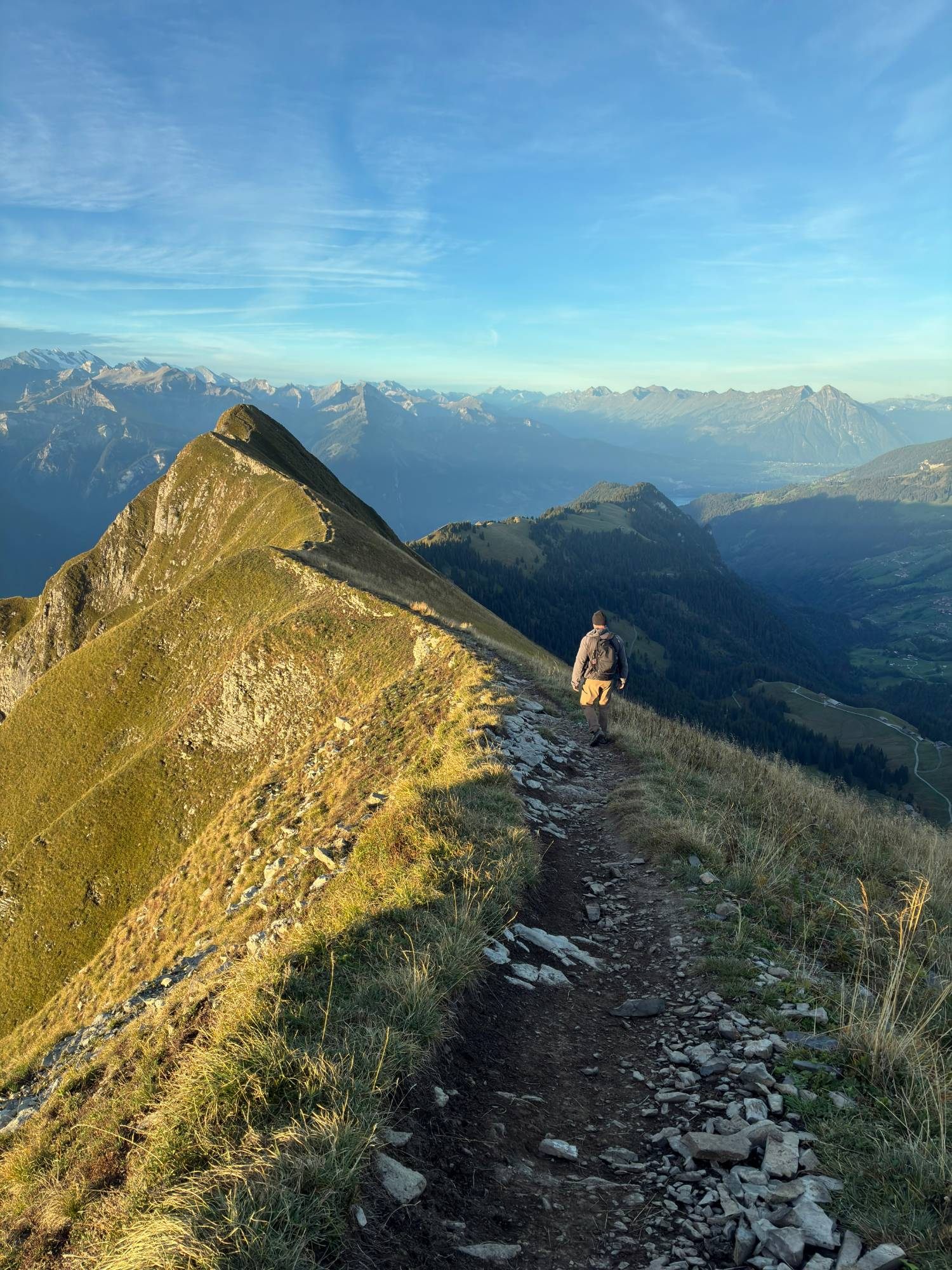Walking along the ridge path with steep grassy slopes and a valley below