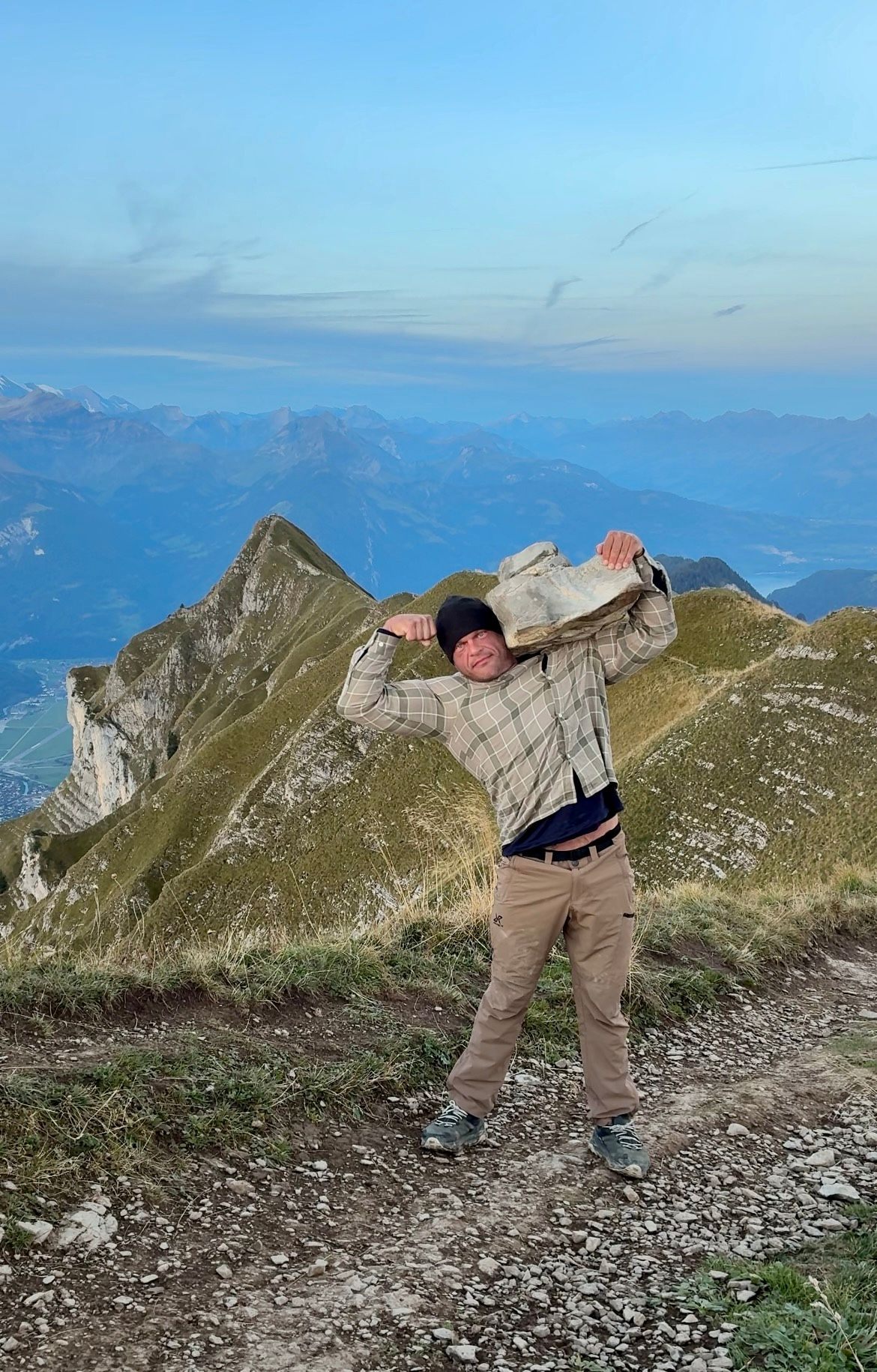 Holding a rock on one shoulder and flexing on the ridge in the blue light before sunrise