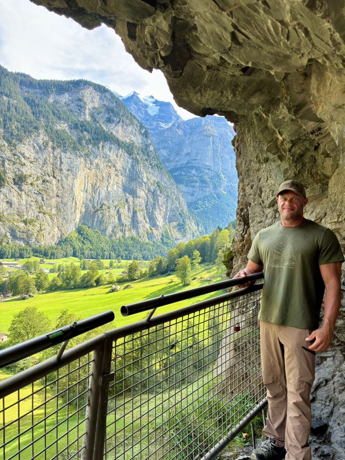 Standing at the railing of the rock gallery by Staubbach Falls, looking out over the green Lauterbrunnen Valley