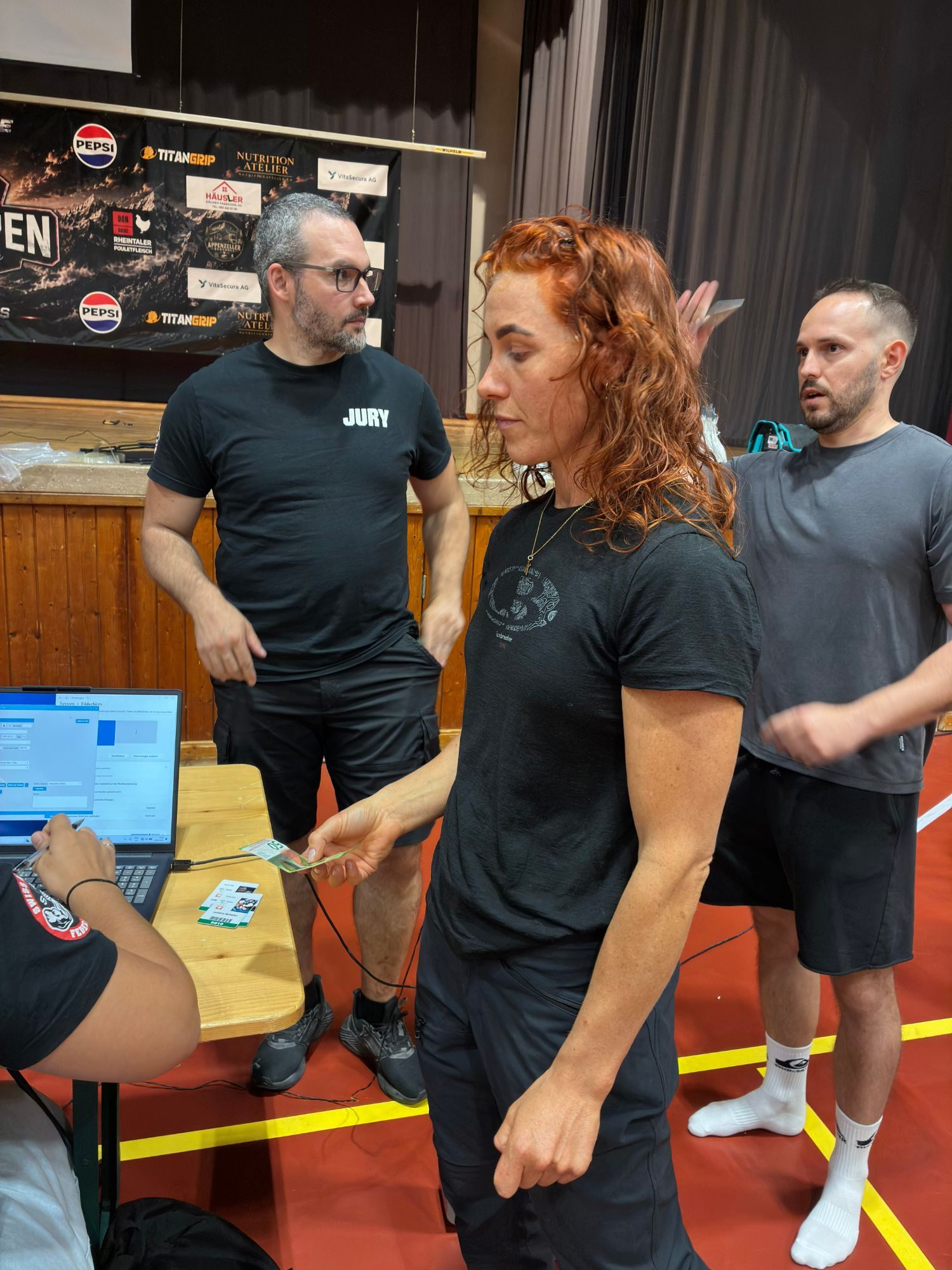 Kristine at the weigh-in table in the Rüeggerholz Halle, with a jury member and a laptop beside her