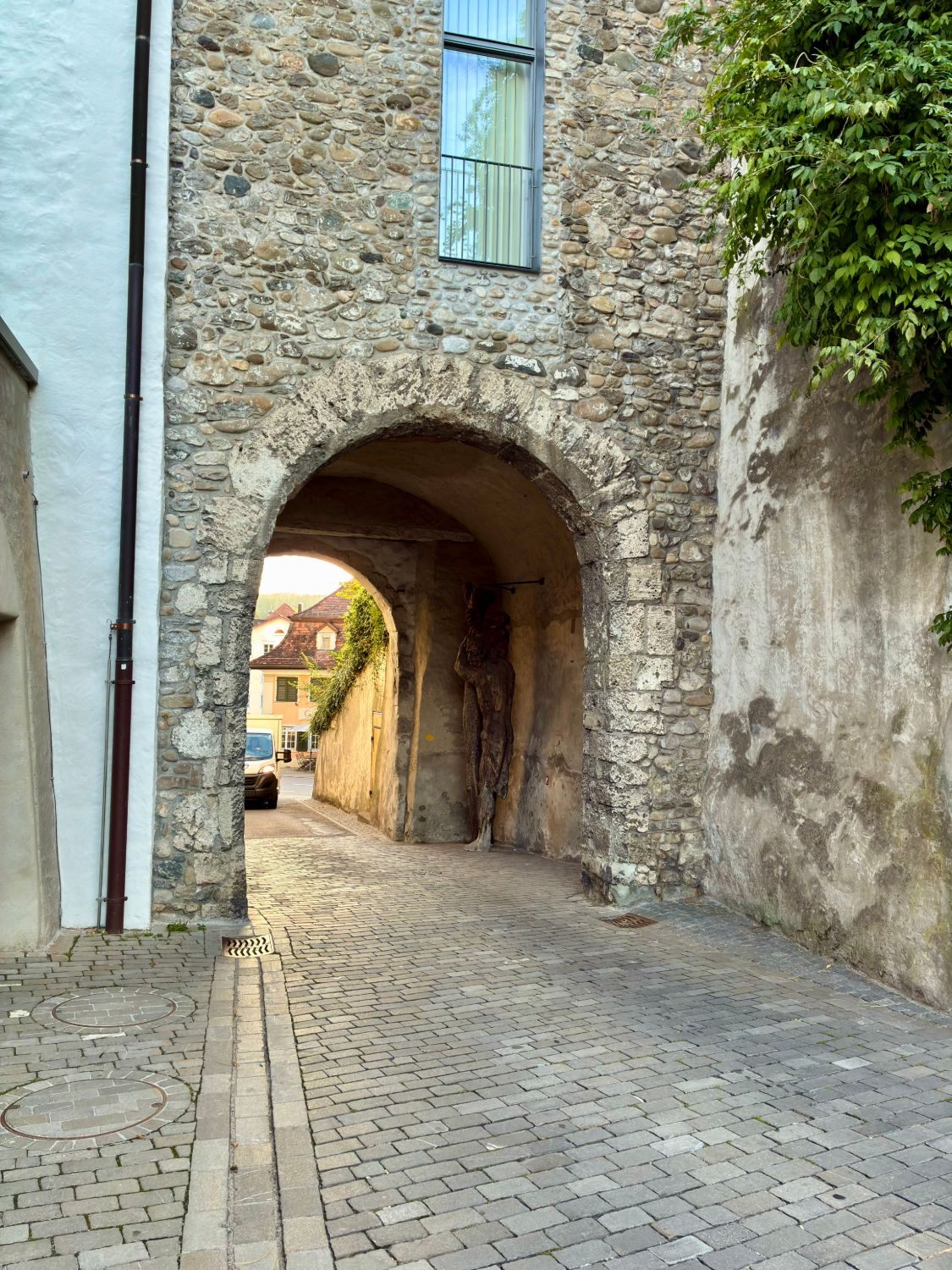 An old stone gateway in Wil with a wooden statue inside the arch