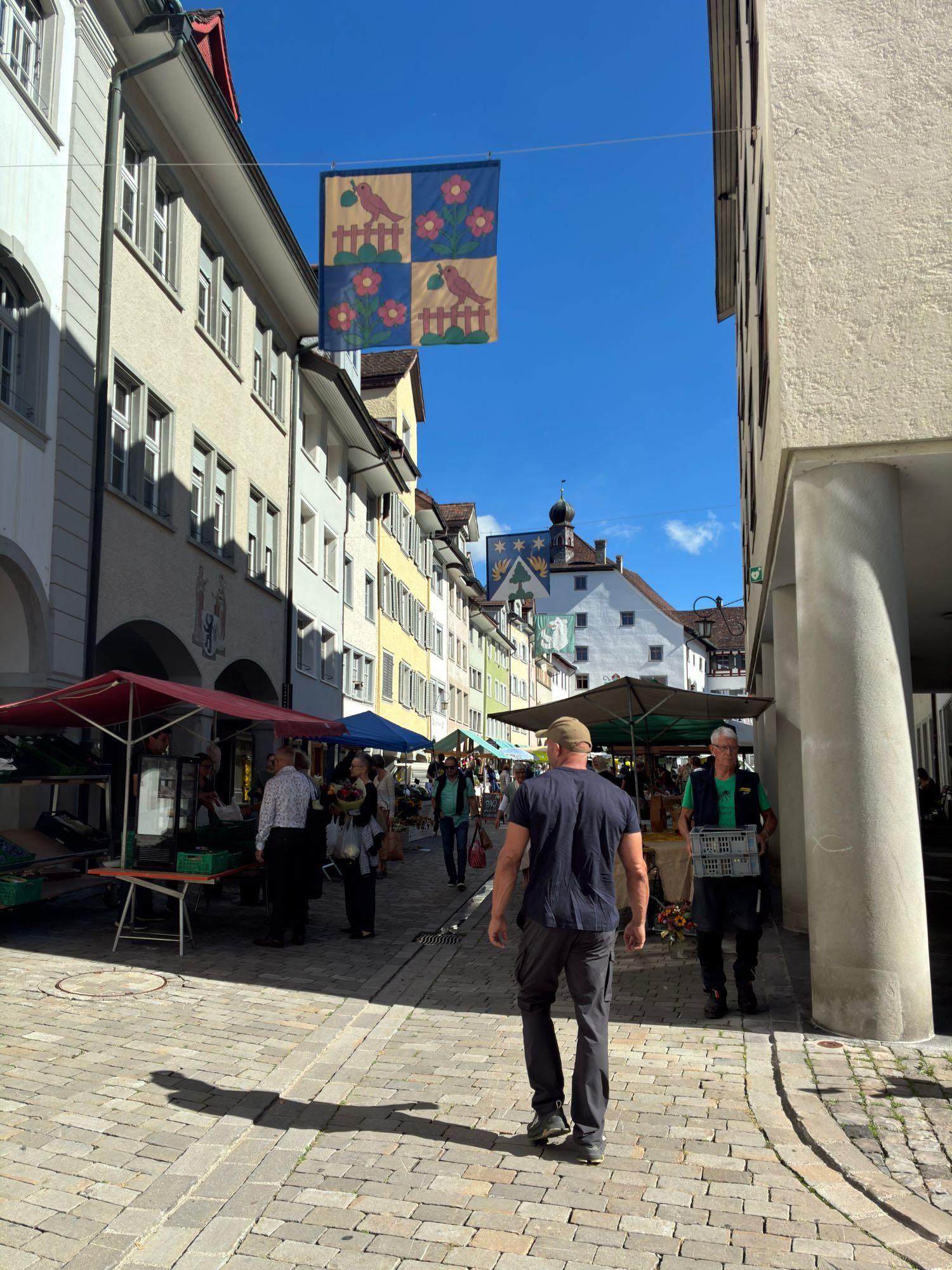 Walking through the market in Wil's old town, with stalls, flags and an onion-domed tower