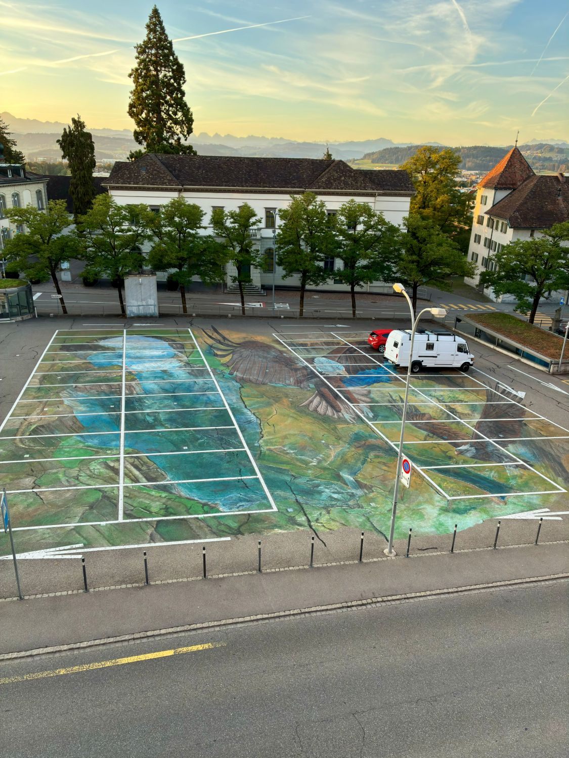 A car park in Wil painted with a large mural of a lake landscape and flying eagles, seen from above