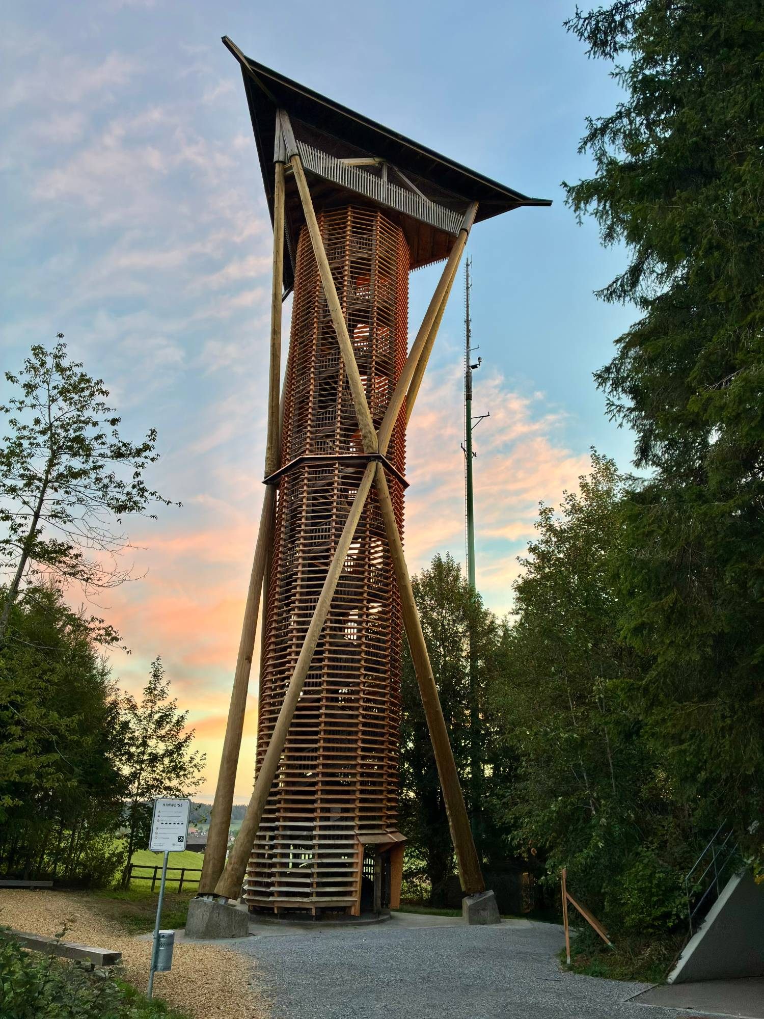 The tall wooden Wiler Turm lookout tower with crossed timber supports, against a pink dawn sky