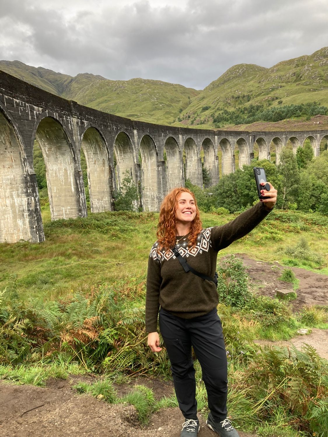 Kristine taking a selfie in front of the long curve of Glenfinnan Viaduct