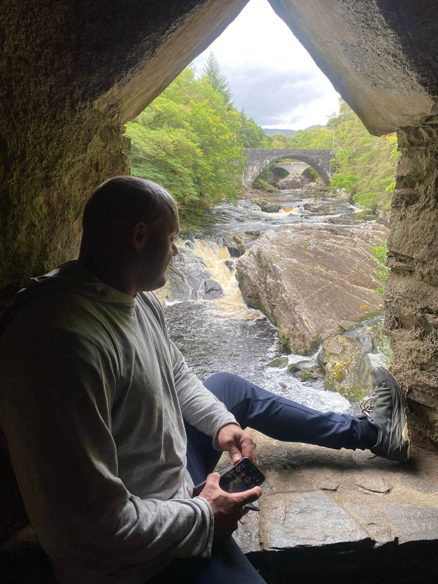 Leif sitting in the pointed window with the falls and the stone bridges behind