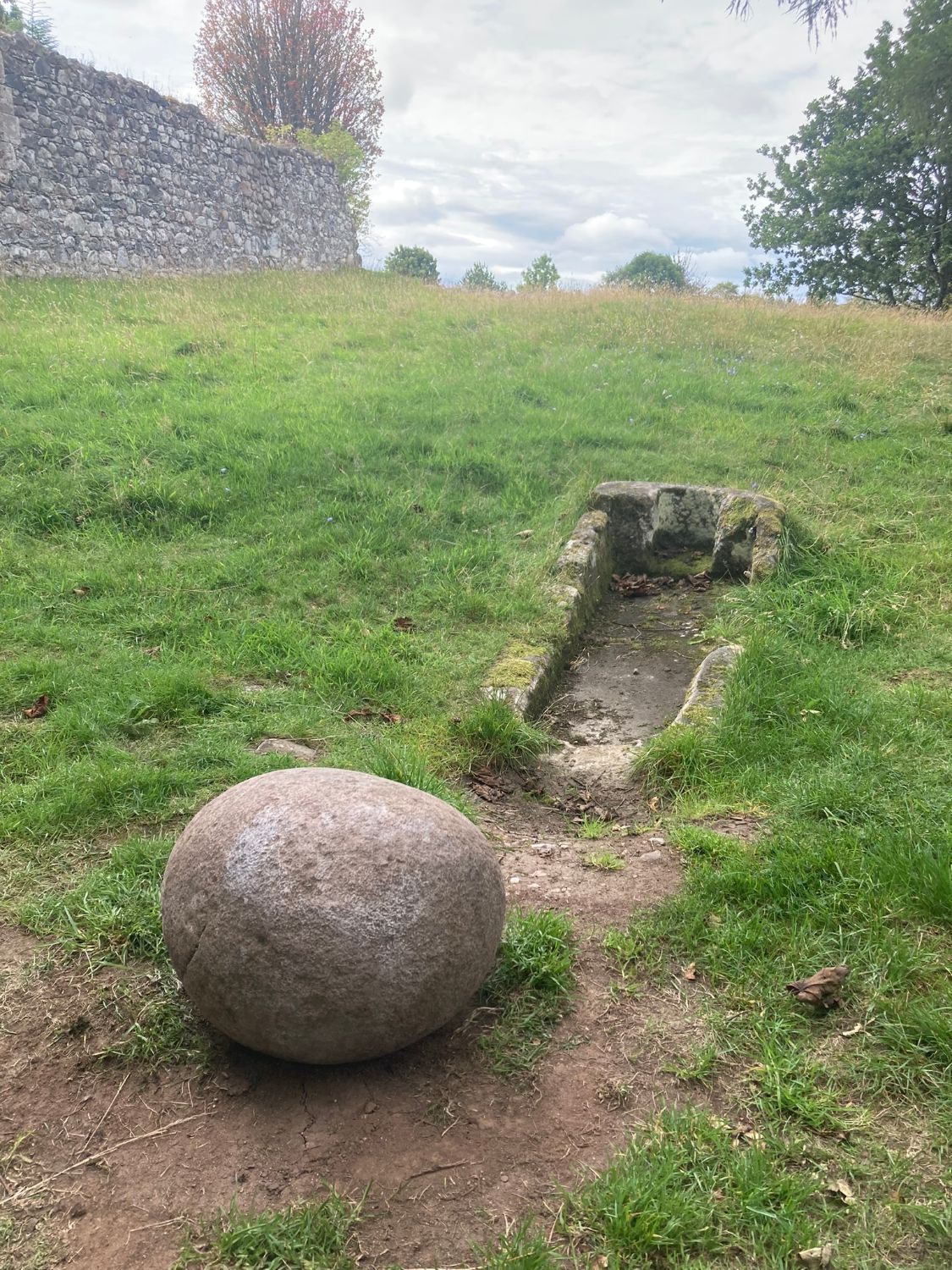 The Barevan Stone in front of the narrow stone sarcophagus, with the old church wall behind