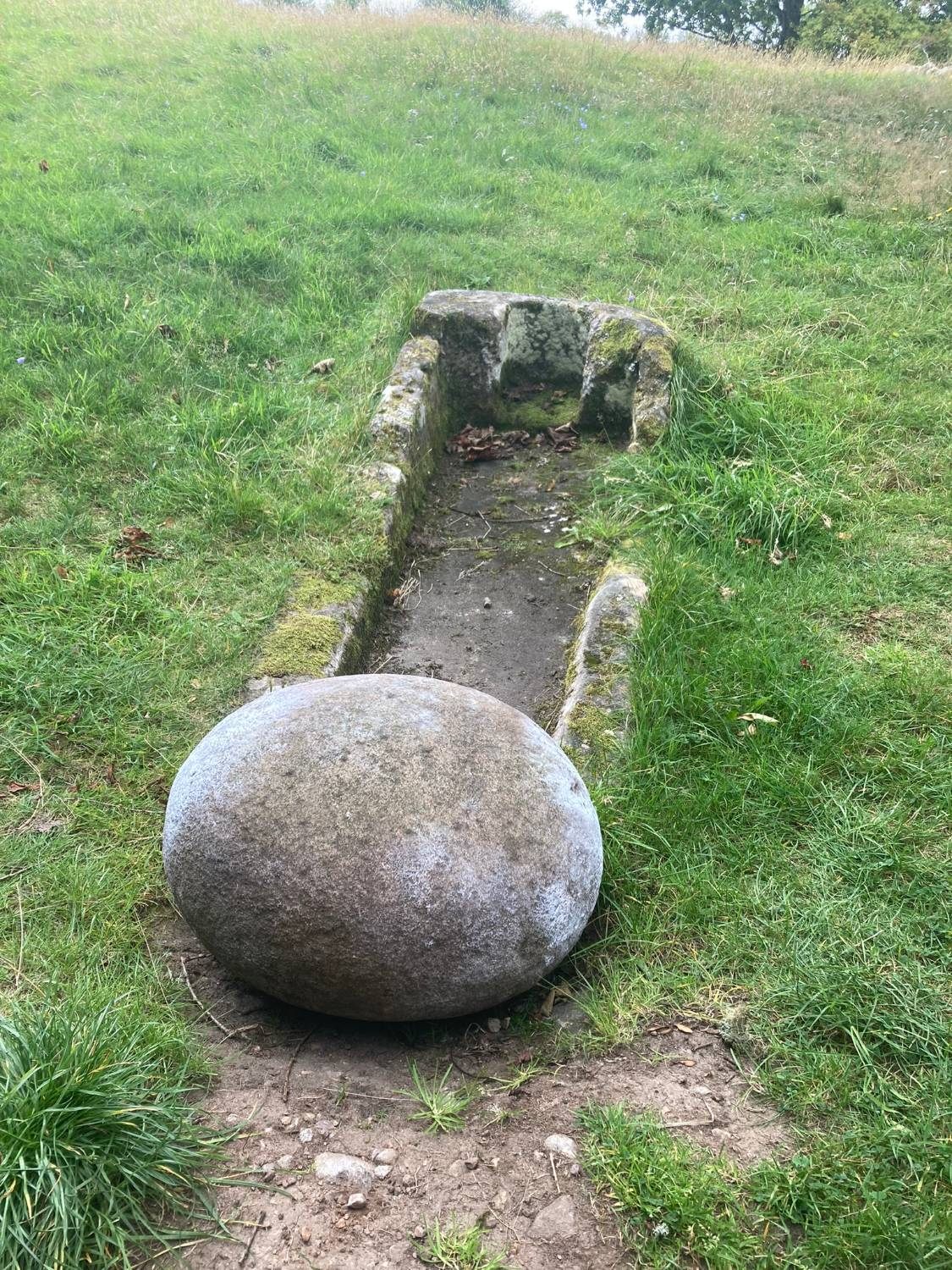 The oval Barevan Stone lying at the foot of a stone sarcophagus in the grass