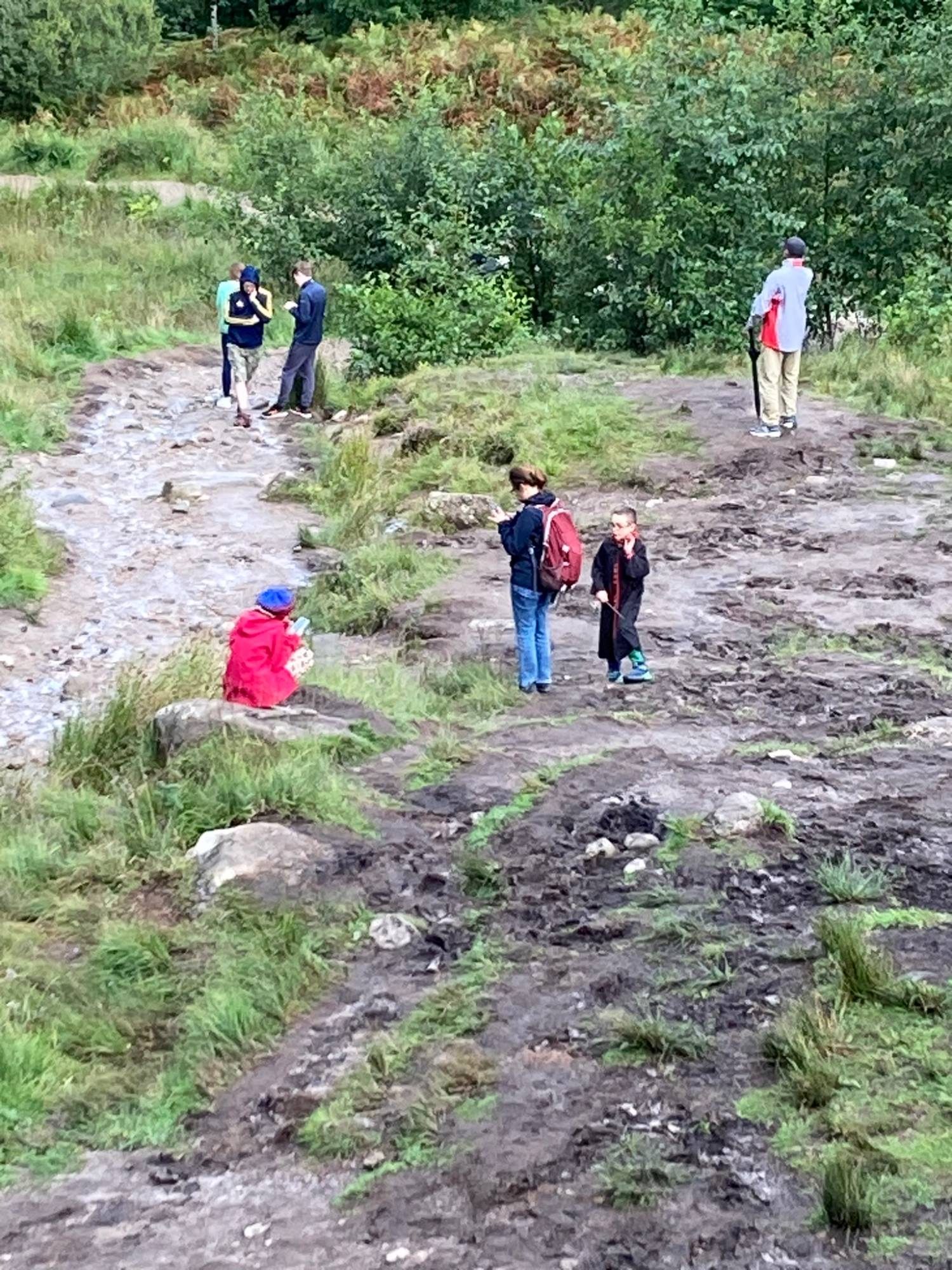 Visitors on a muddy path near the viaduct, including a child in a wizard robe holding a wand