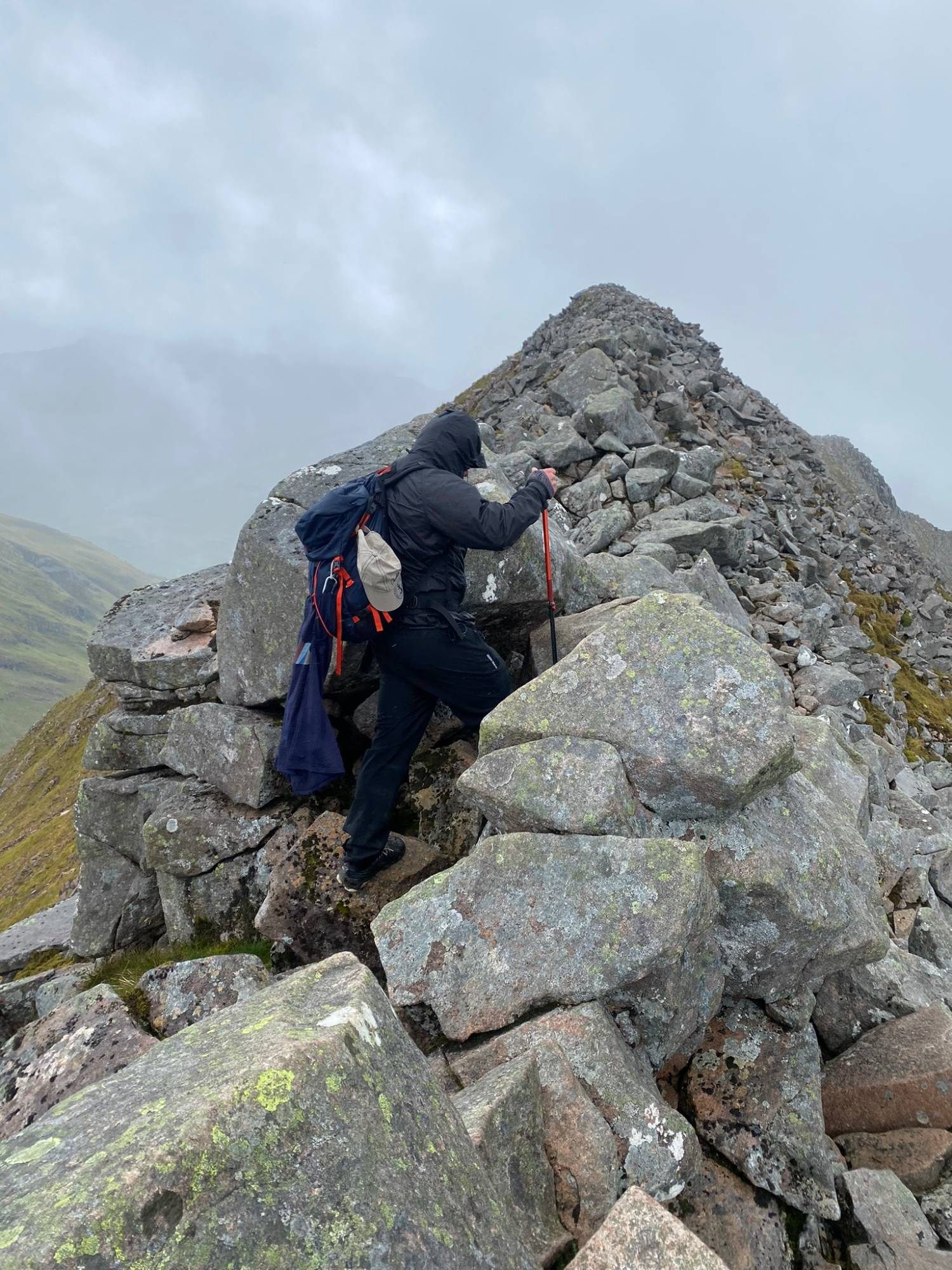 Leif using a trekking pole to step up over large boulders on the CMD Arête