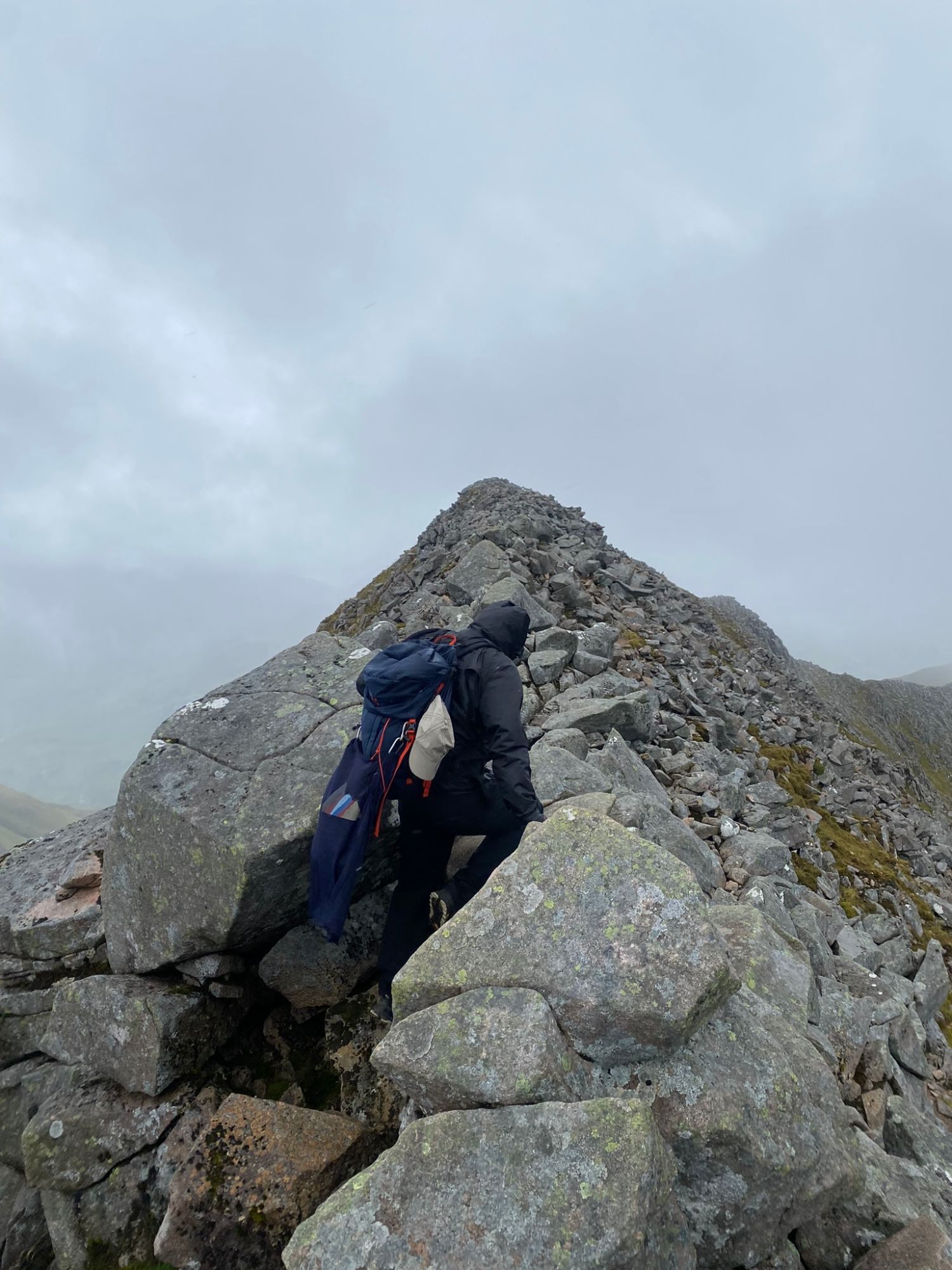 Leif with a blue backpack climbing over large granite boulders on the ridge