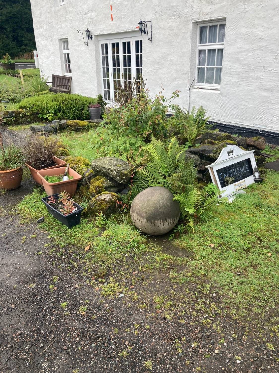 The round MacGregor Stone resting by the ferns next to the hotel entrance sign