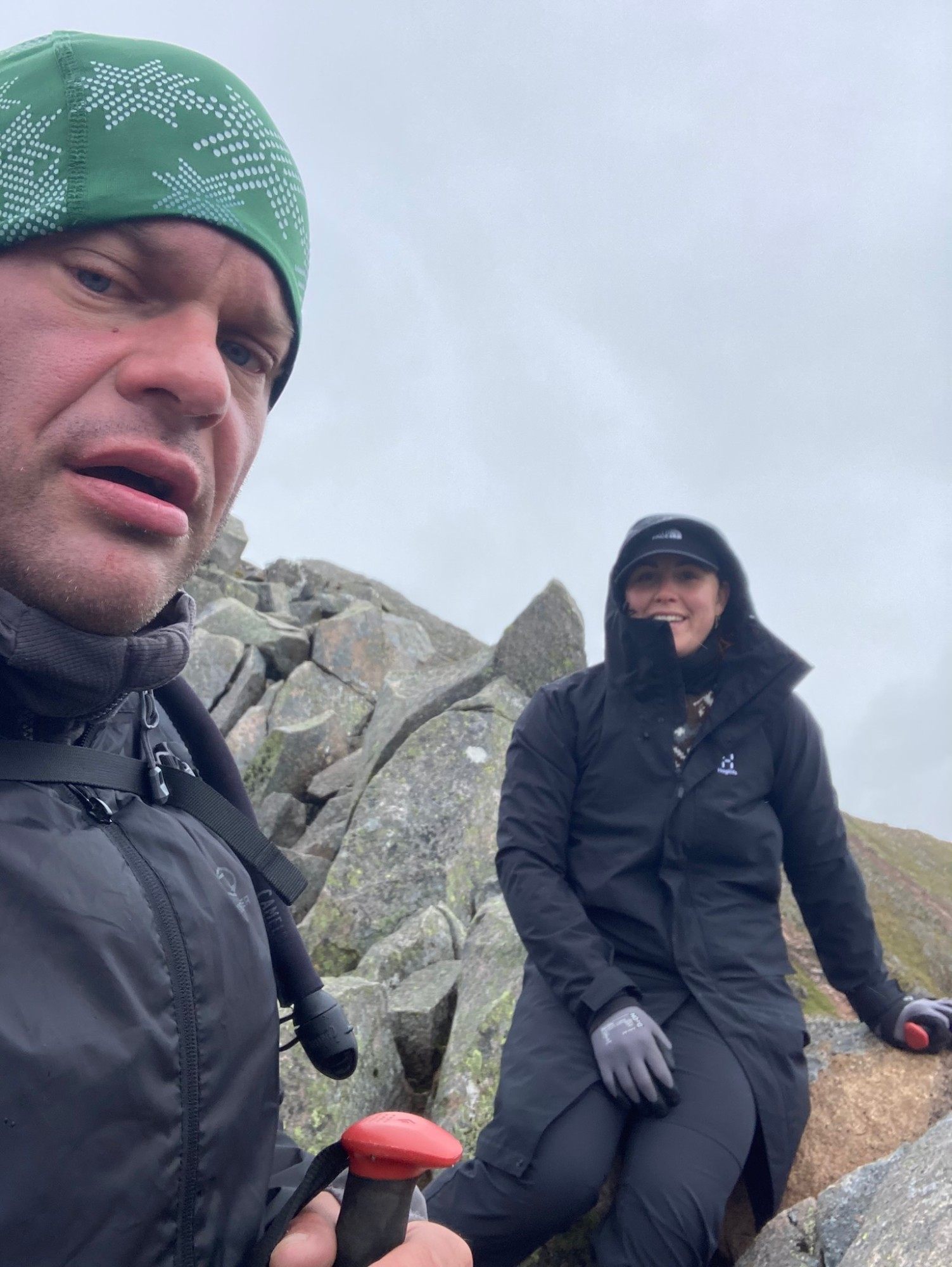 Leif pulling a face in a selfie with Kristine sitting on the rocks behind him on the ridge