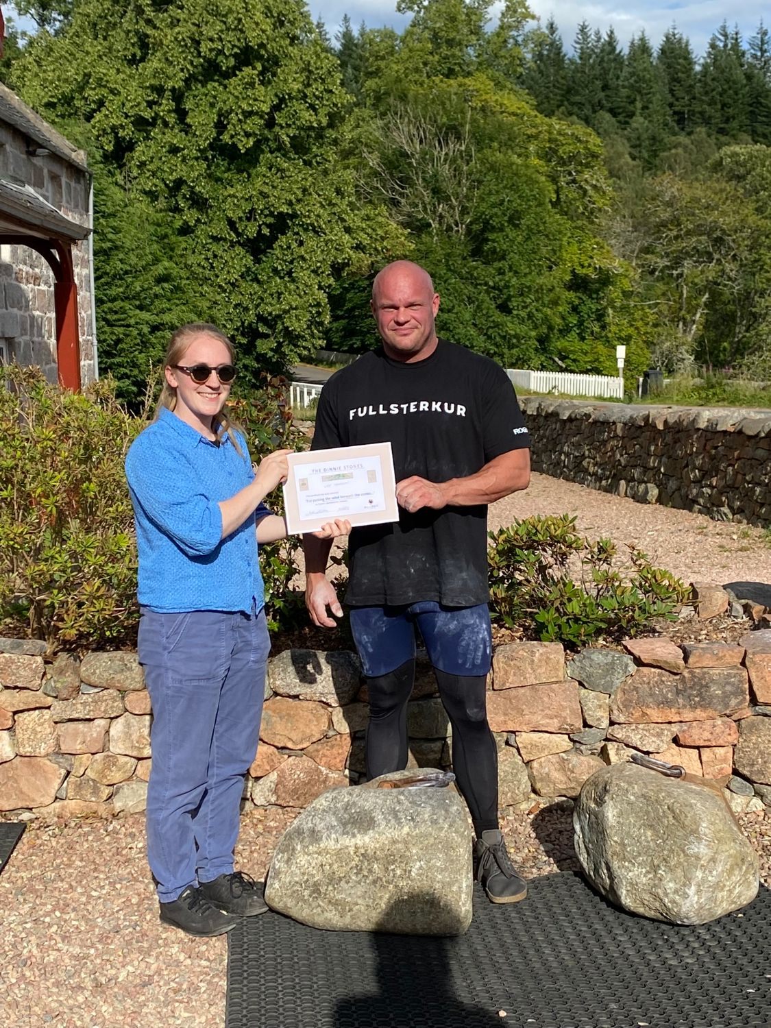 Holding the Dinnie Stones certificate after the lift, standing behind the two stones