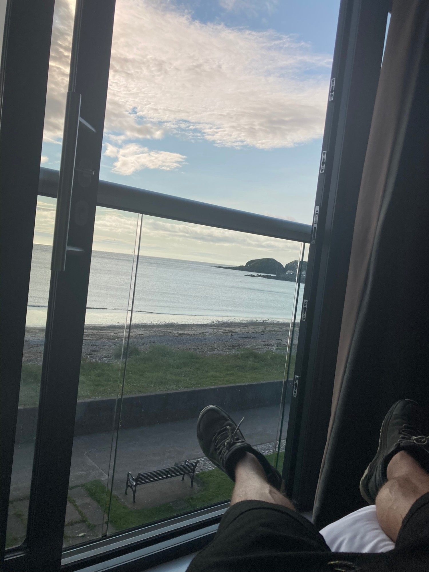 Feet up on the window sill of our room at Number 44, looking out over the beach, a bench and the sea in Stonehaven