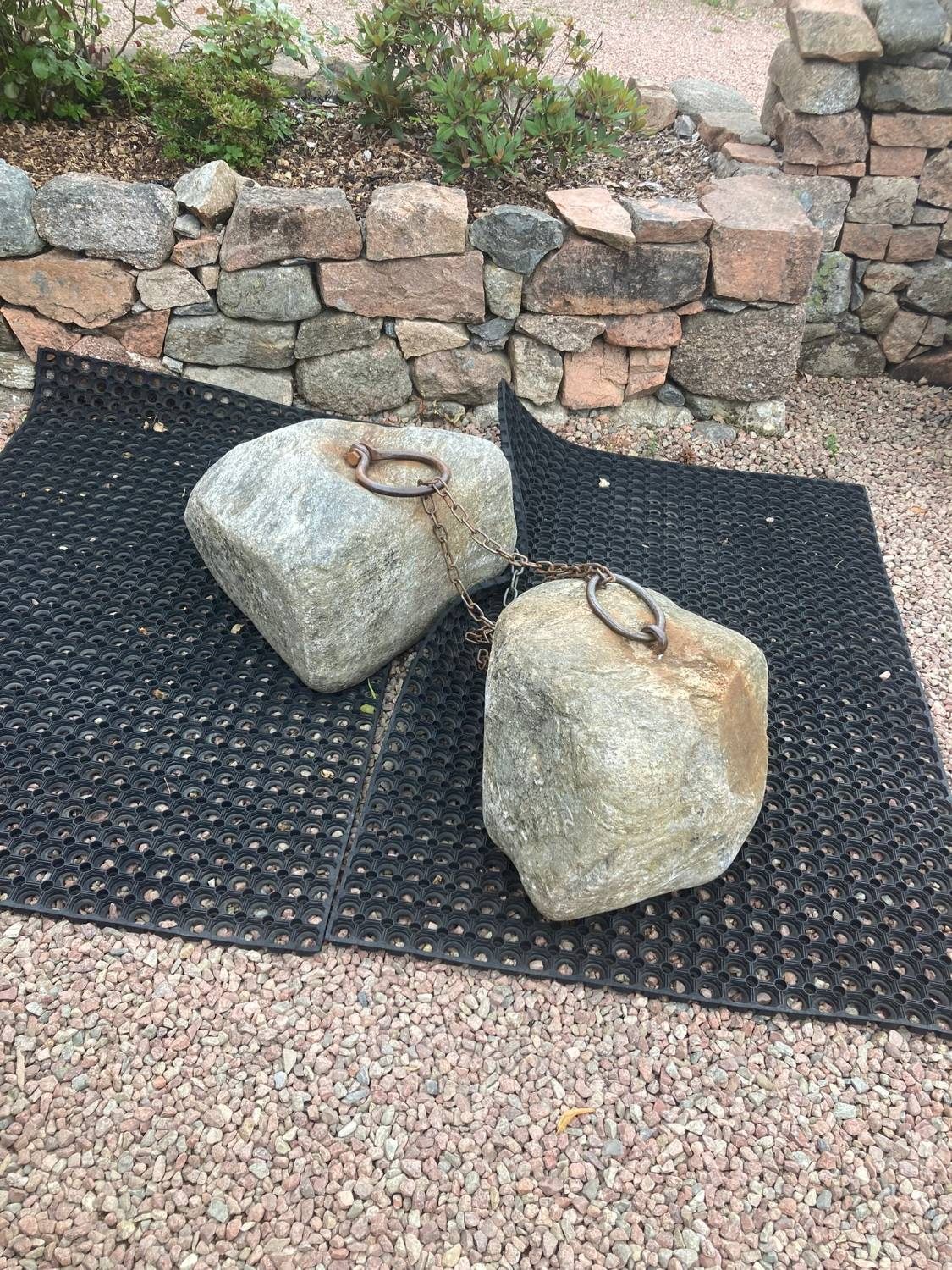 The two Dinnie Stones on rubber mats, joined by a chain through their iron rings