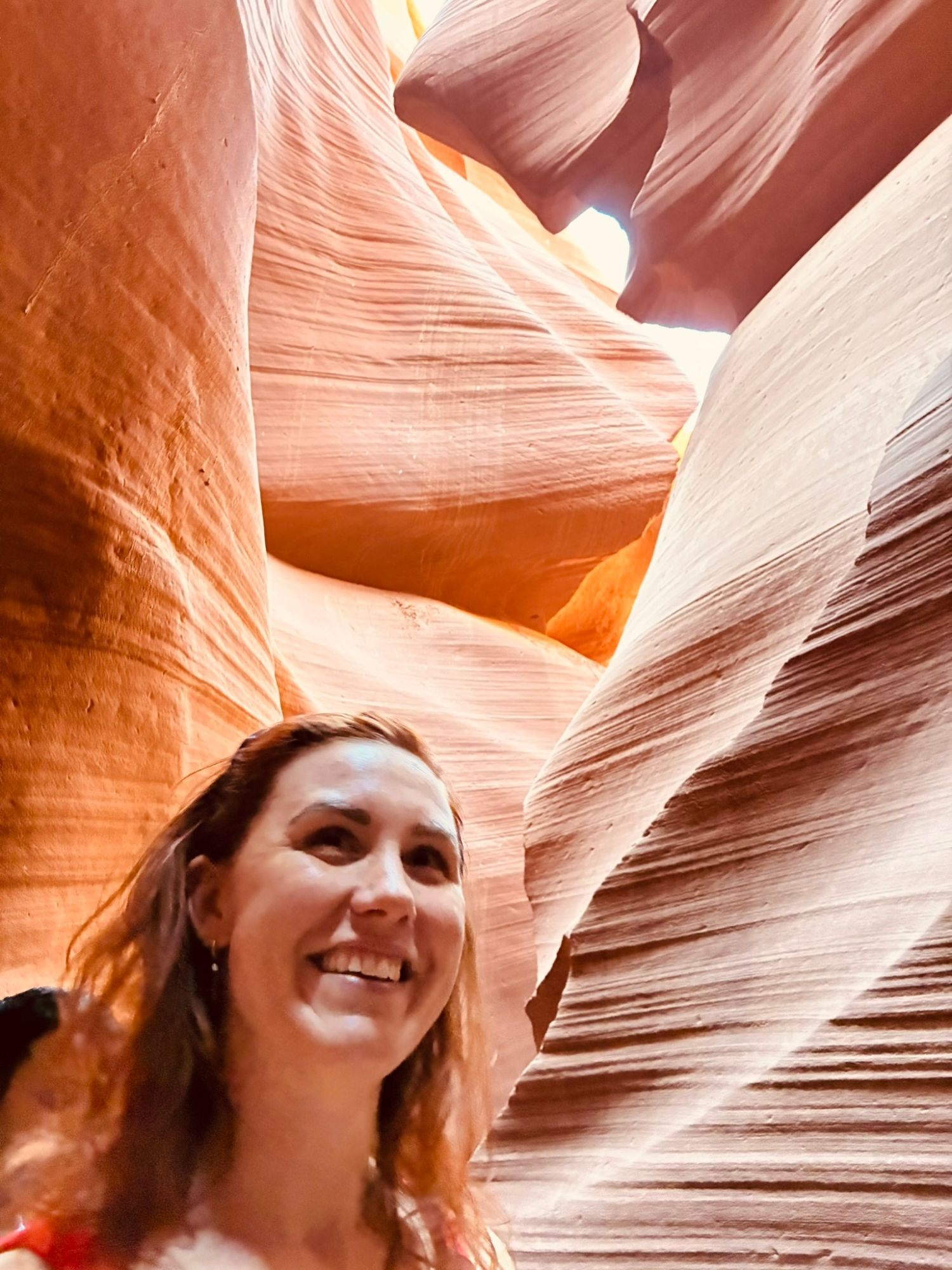 Kristine smiling and looking up at the sculpted walls of Lower Antelope Canyon