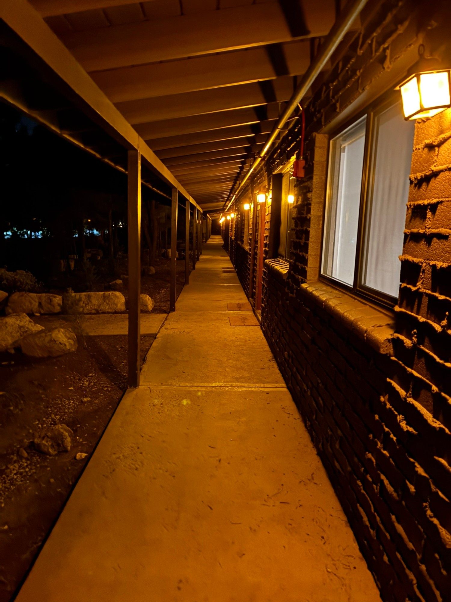The covered walkway along the lodge rooms at Yavapai Lodge at night, lit by warm lanterns