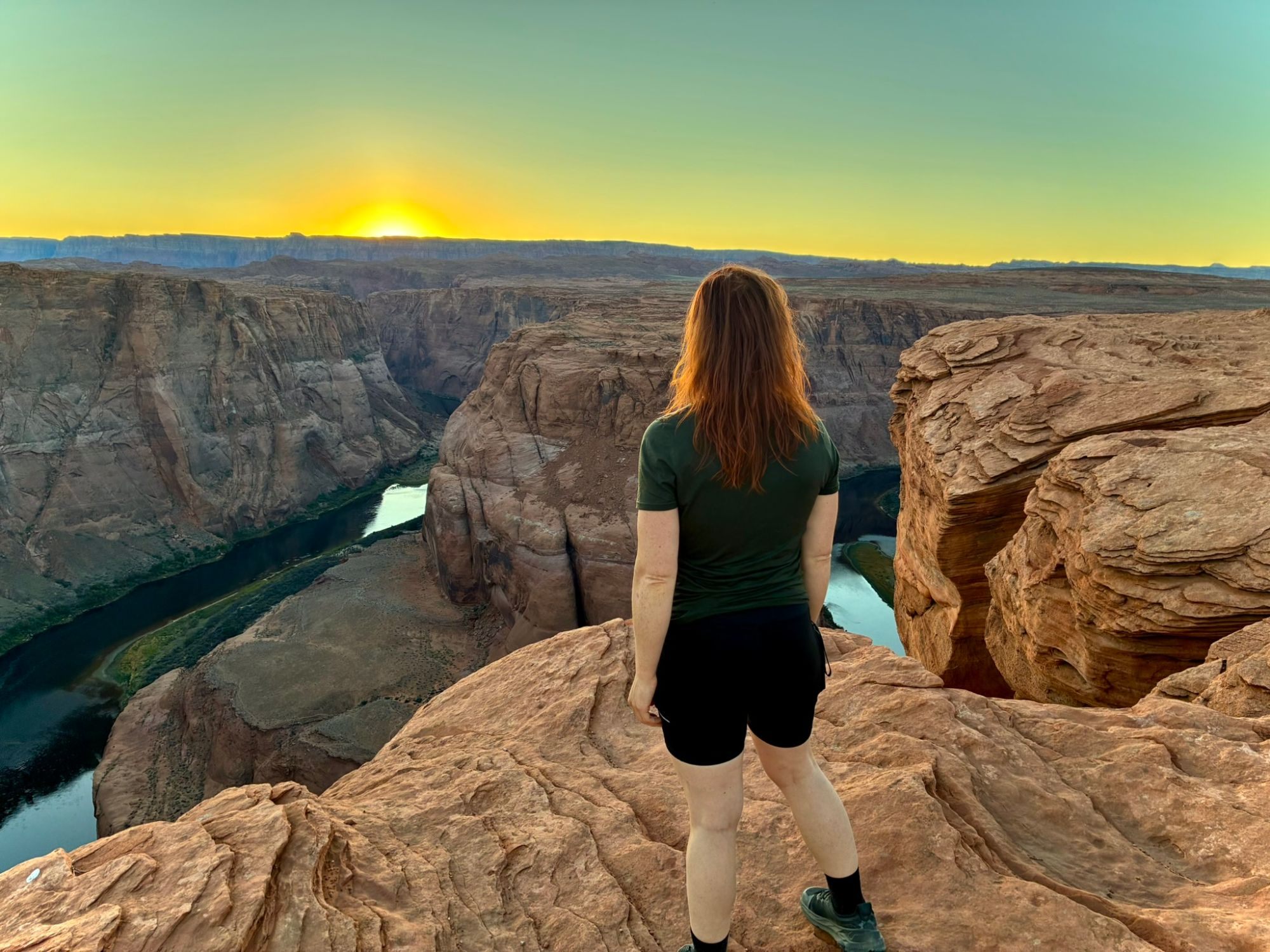 Kristine seen from behind, looking out at the canyon and the setting sun