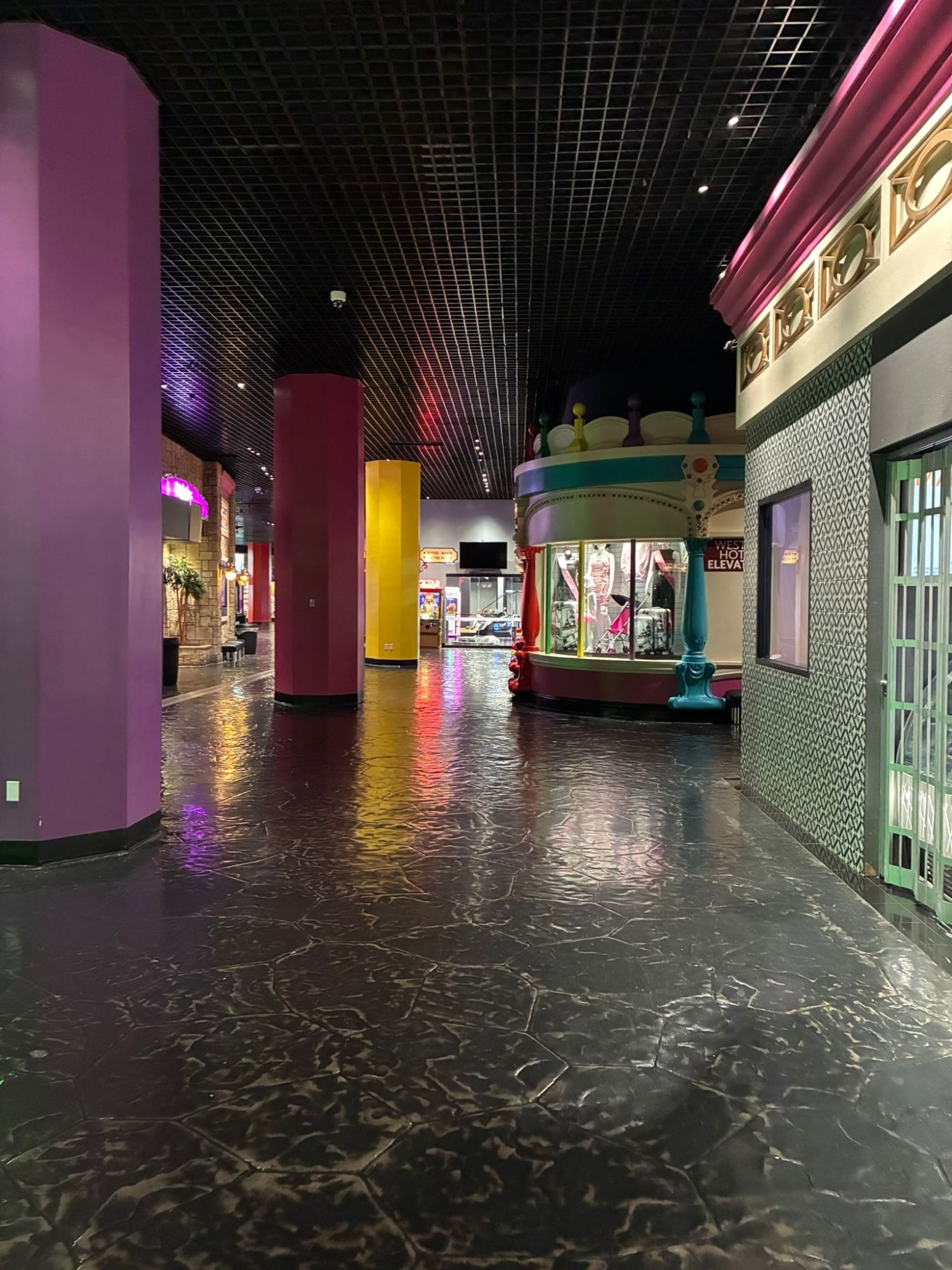 A long, colourful corridor inside Circus Circus with purple, red and yellow pillars and a shiny dark floor