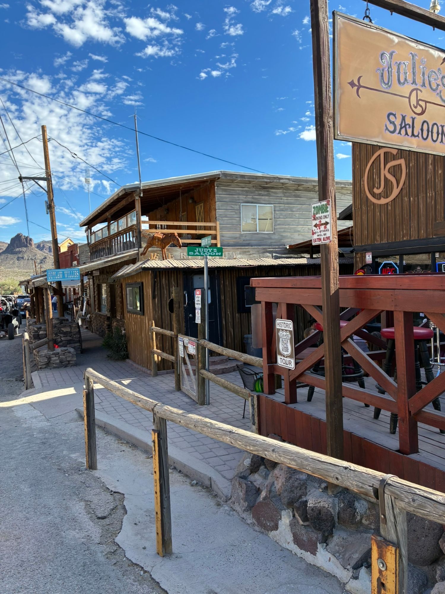 Wooden saloon buildings on Oatman's main street with a Julie's Saloon sign and a Zombie parking only sign
