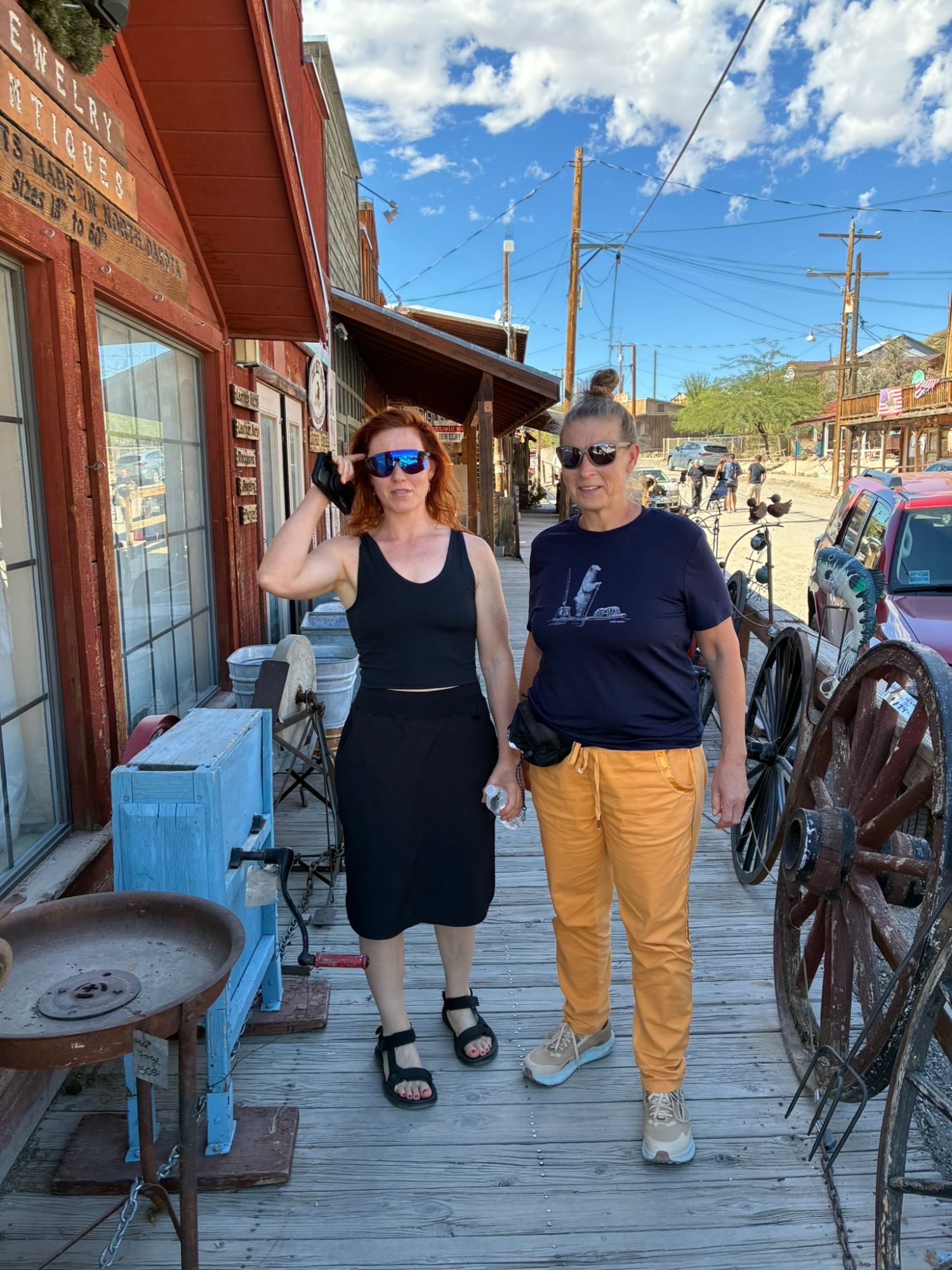 Kristine and Inge on a wooden boardwalk lined with old wagon wheels and tools