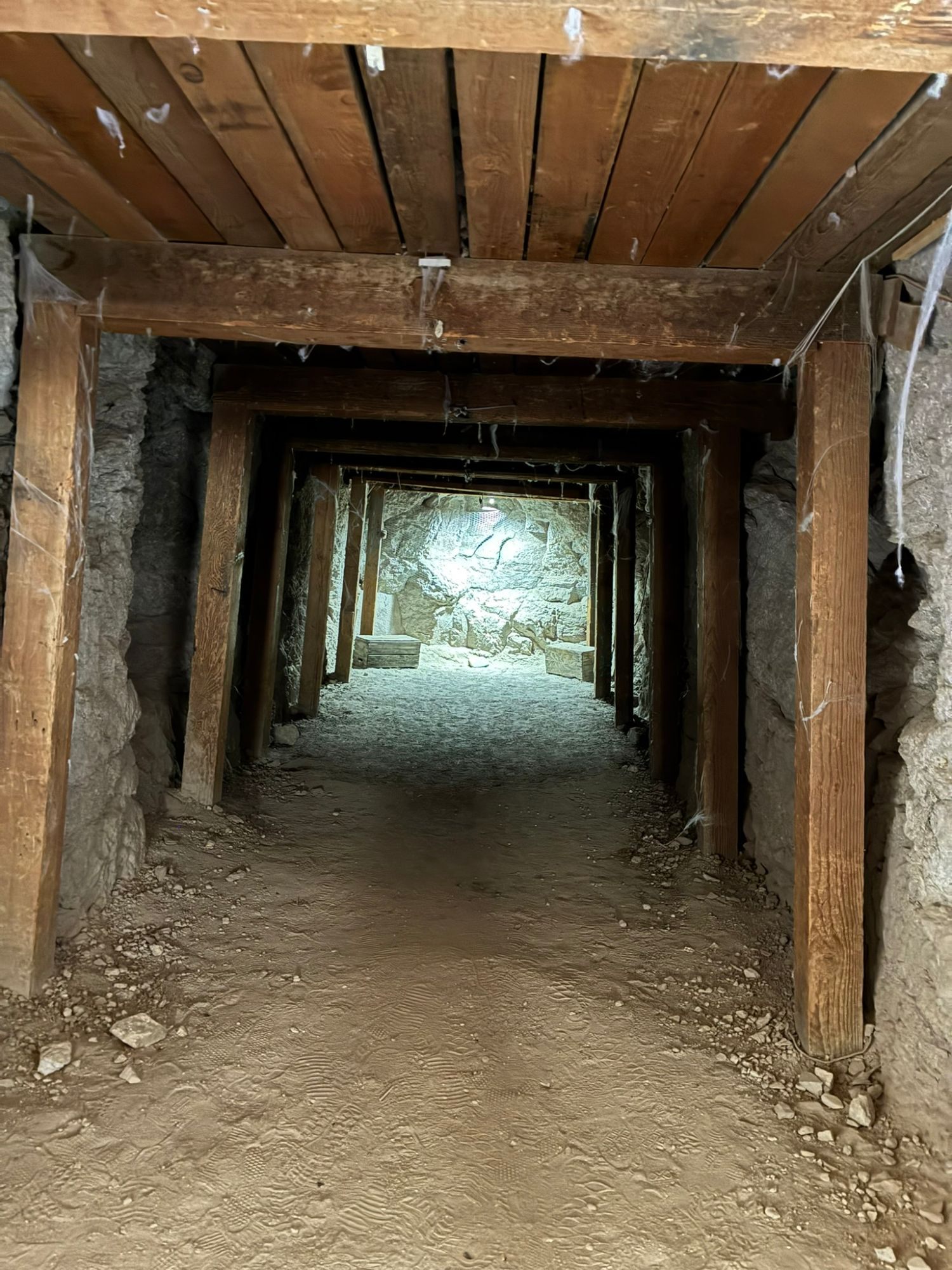 A timber-framed mine tunnel leading into lit rock