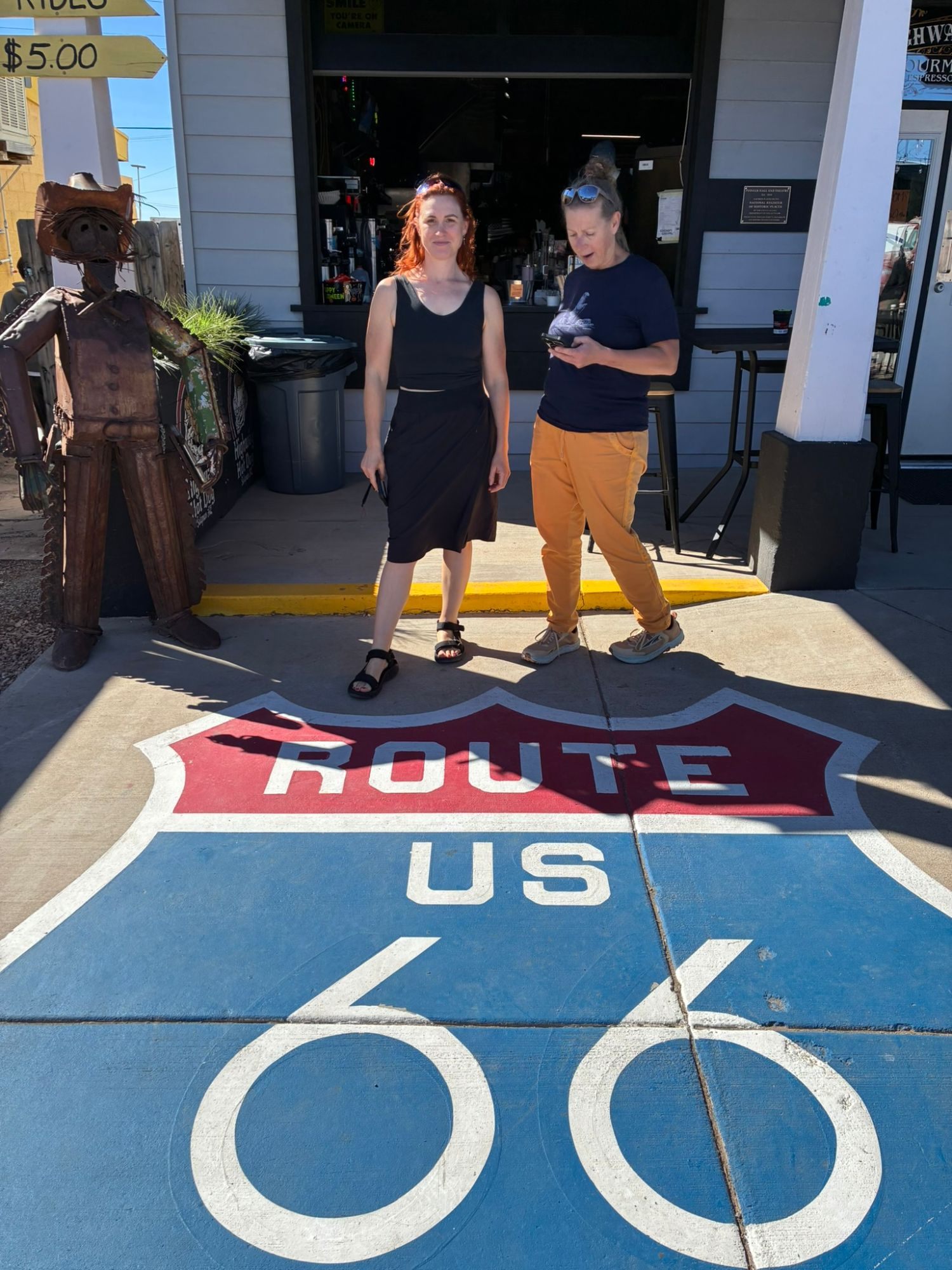 Kristine and Inge standing behind a big Route 66 shield painted on the pavement in Seligman