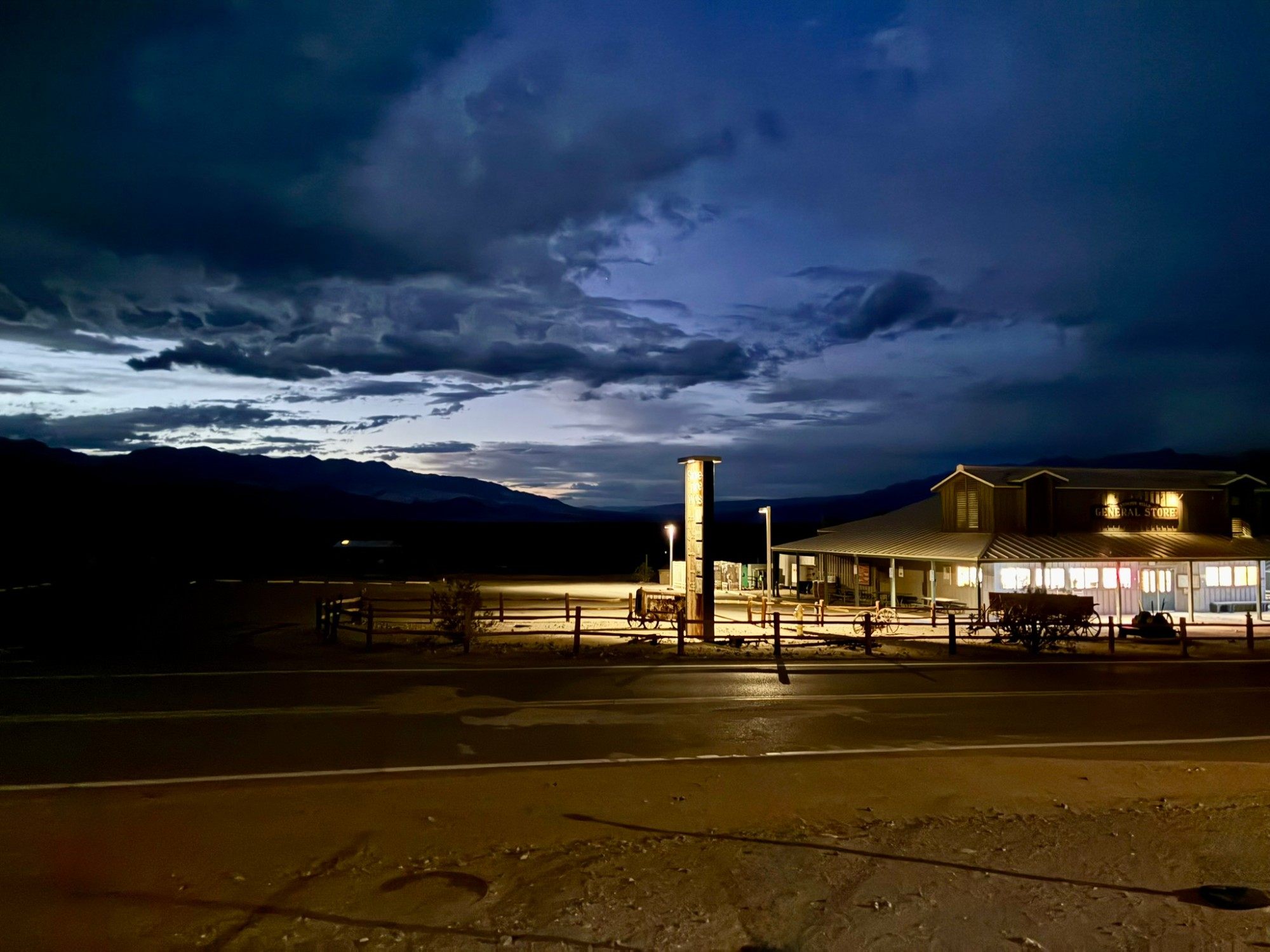 The Stovepipe Wells General Store lit up at dusk under dark storm clouds