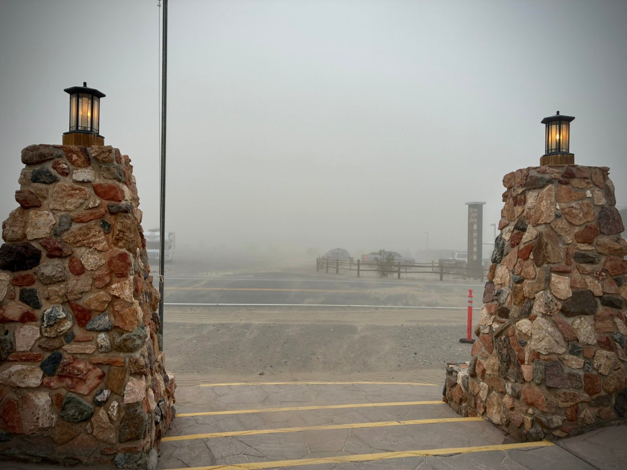 The stone entrance pillars at Stovepipe Wells with the road and campground almost hidden by blowing sand