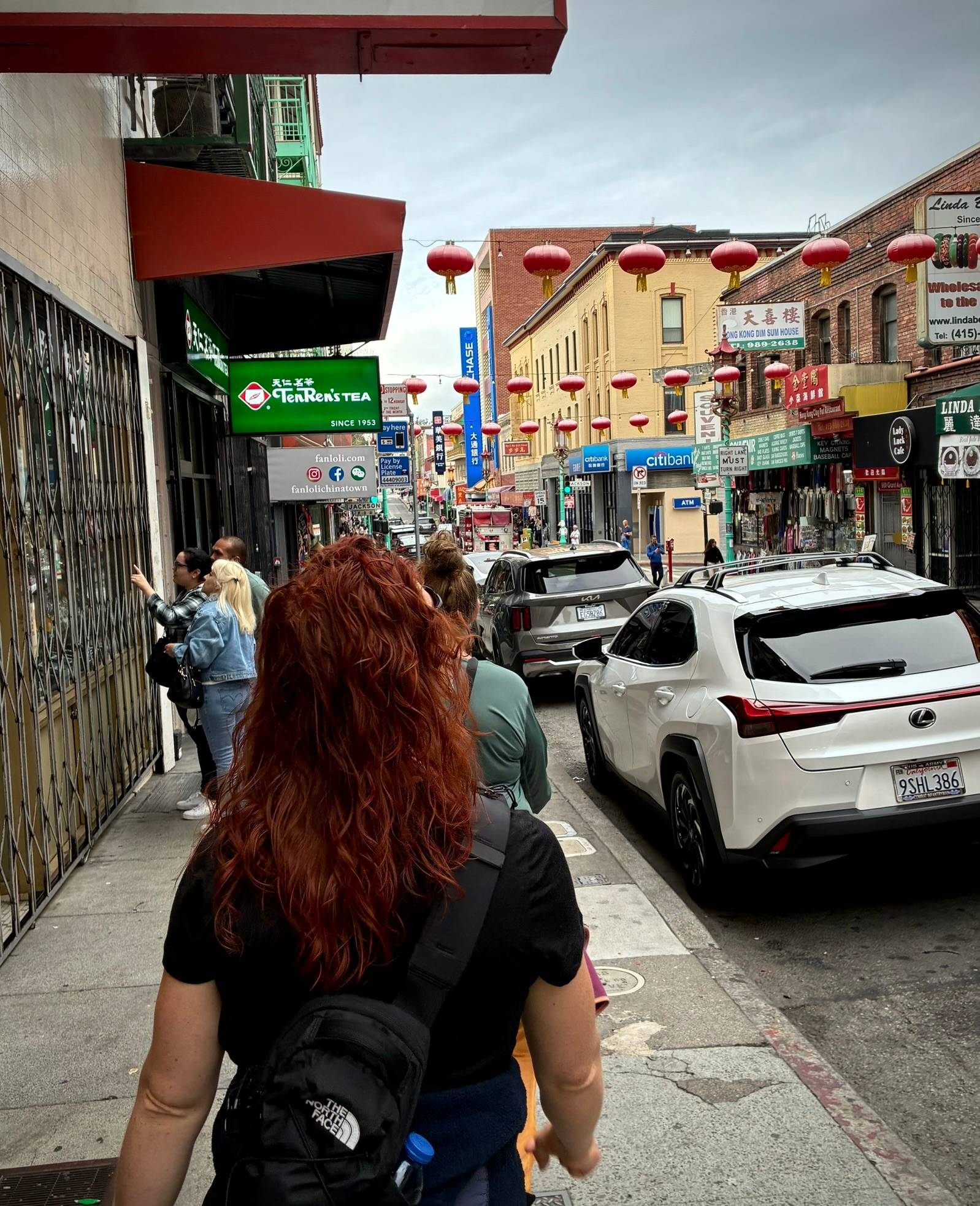Kristine walking along a busy Chinatown street with red lanterns, shop signs and traffic