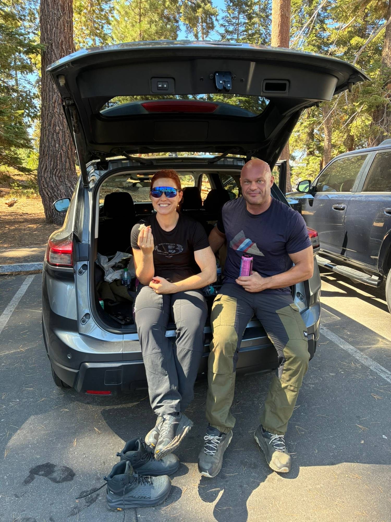 Kristine and me sitting in the open boot of the rental car in the parking area, eating our packed food
