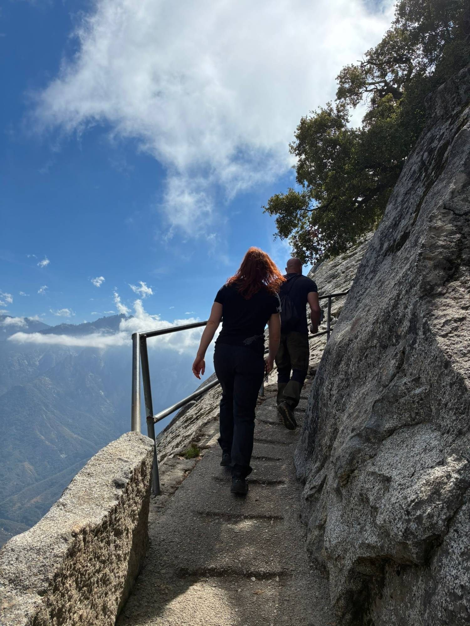 Kristine and me climbing the railed steps on Moro Rock with mountains and clouds beside us