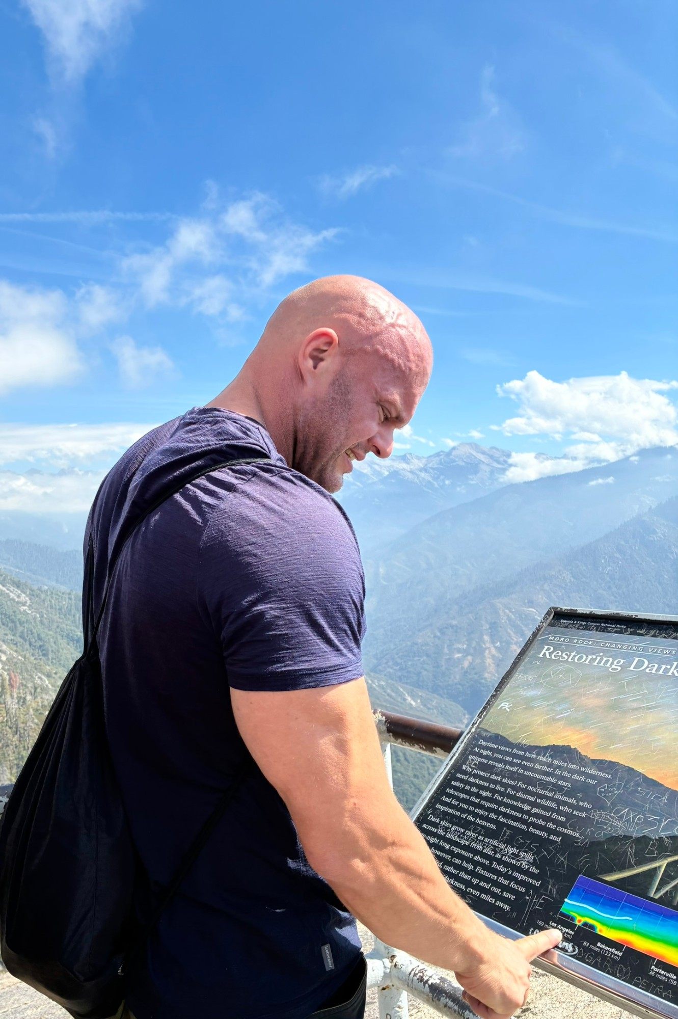 Reading a park information sign at the top of Moro Rock, with mountains and haze behind