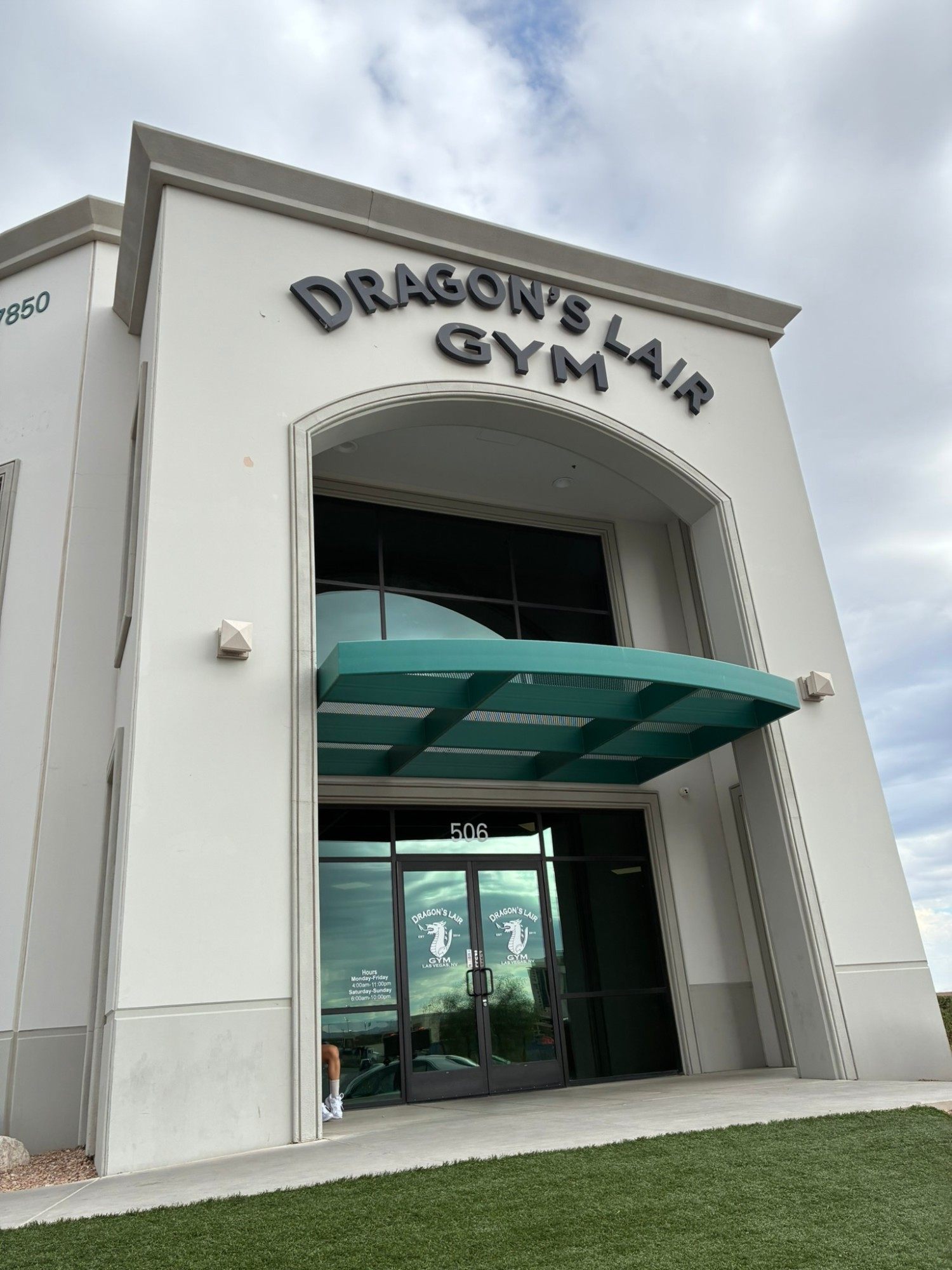 The entrance to Dragon's Lair Gym in Las Vegas, a white building with a green canopy