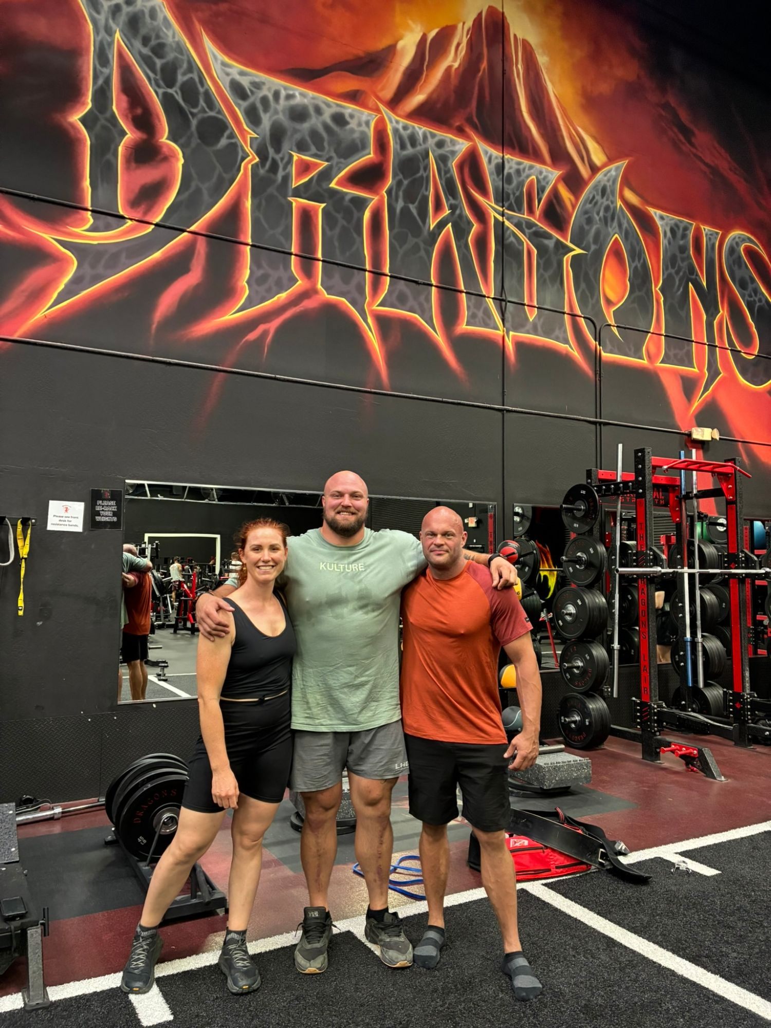 Kristine, Mitchell Hooper and Leif with arms around each other in front of the Dragons mural